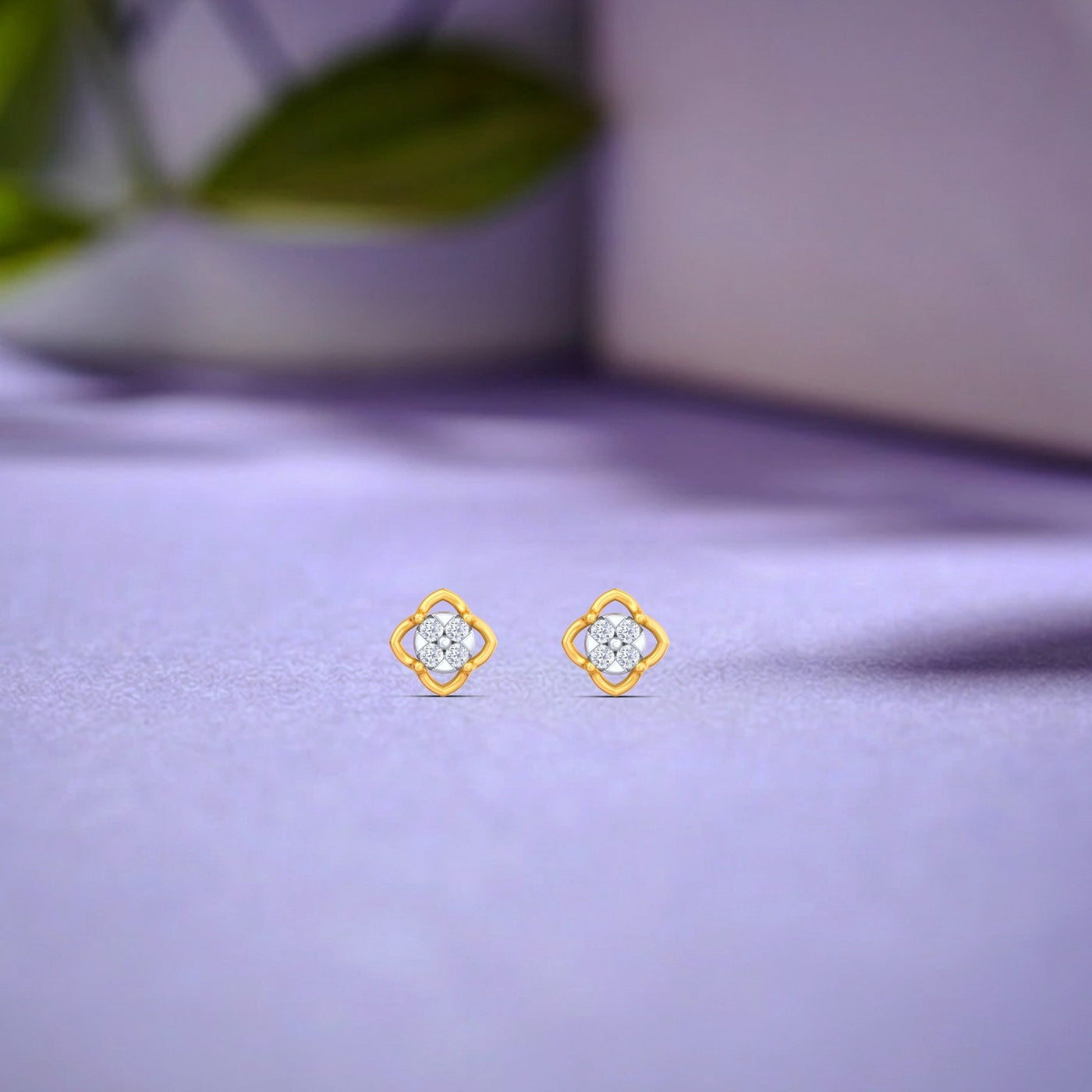 Gold and diamond stud earrings on a purple fabric background