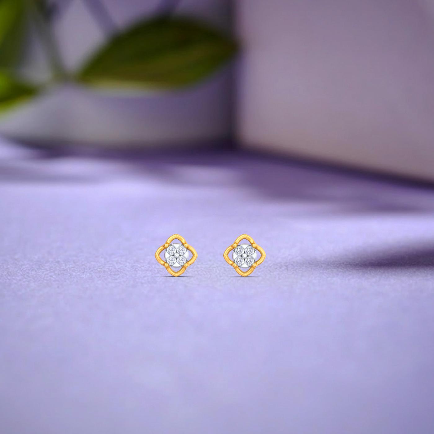 Gold and diamond stud earrings on a purple fabric background