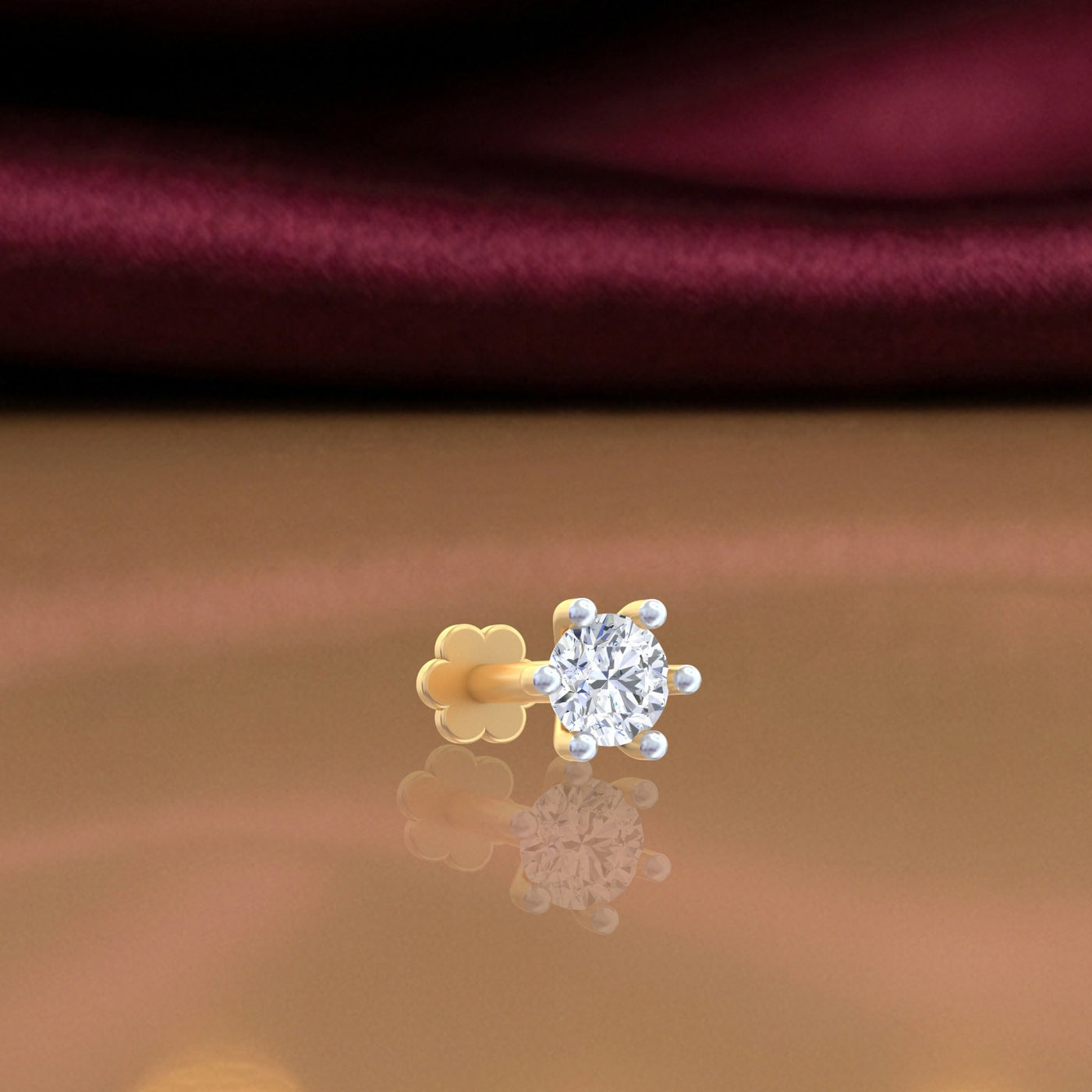 Yellow Gold and diamond stud nose pin on a reflective surface