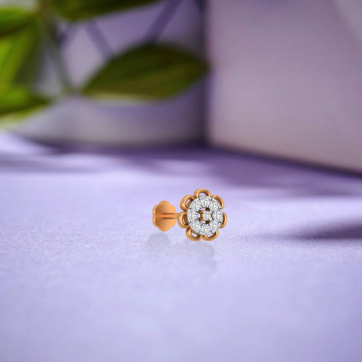 yellow gold and diamond stud nose pin with floral design on a purple surface