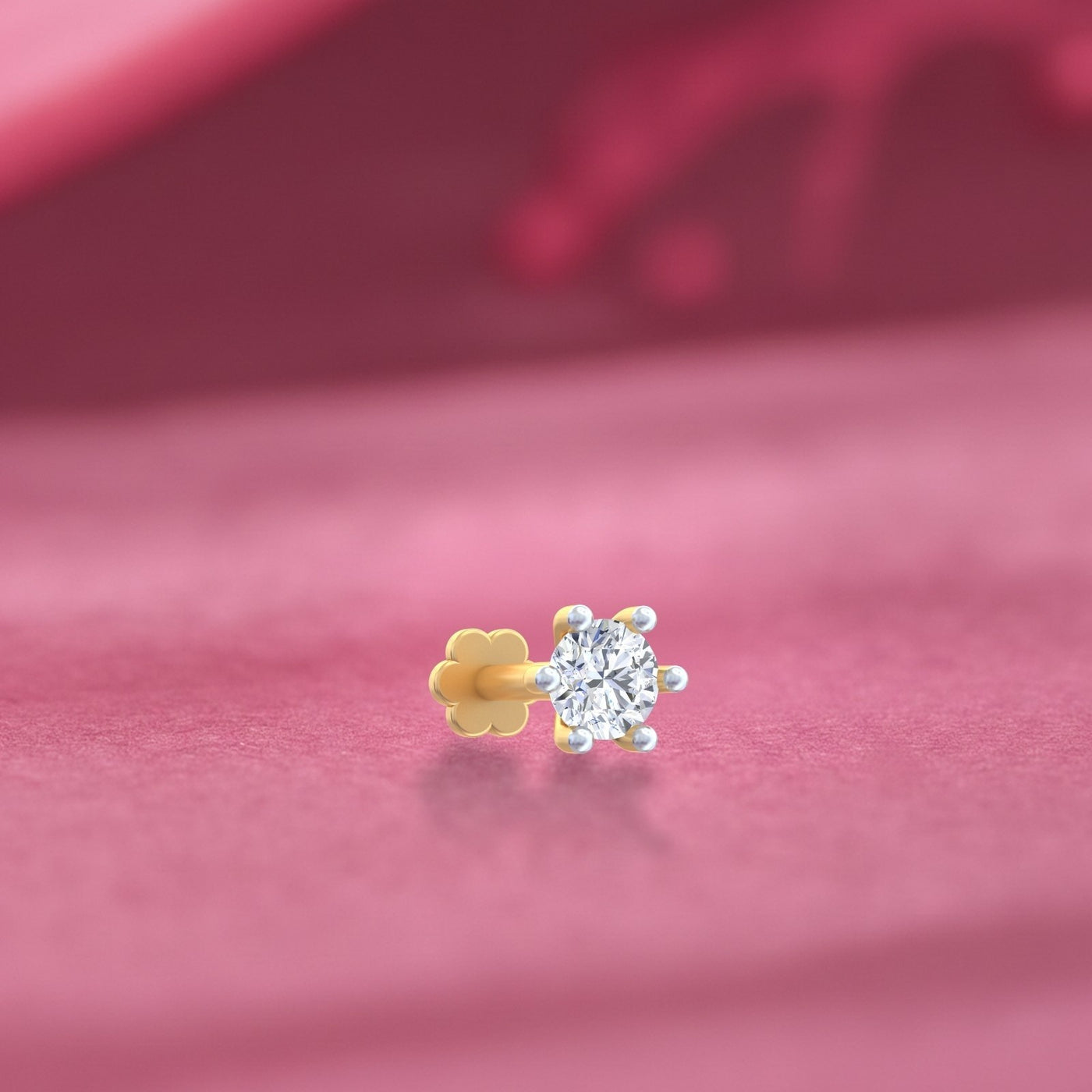 yellow gold and diamond stud nose pin on a pink fabric background