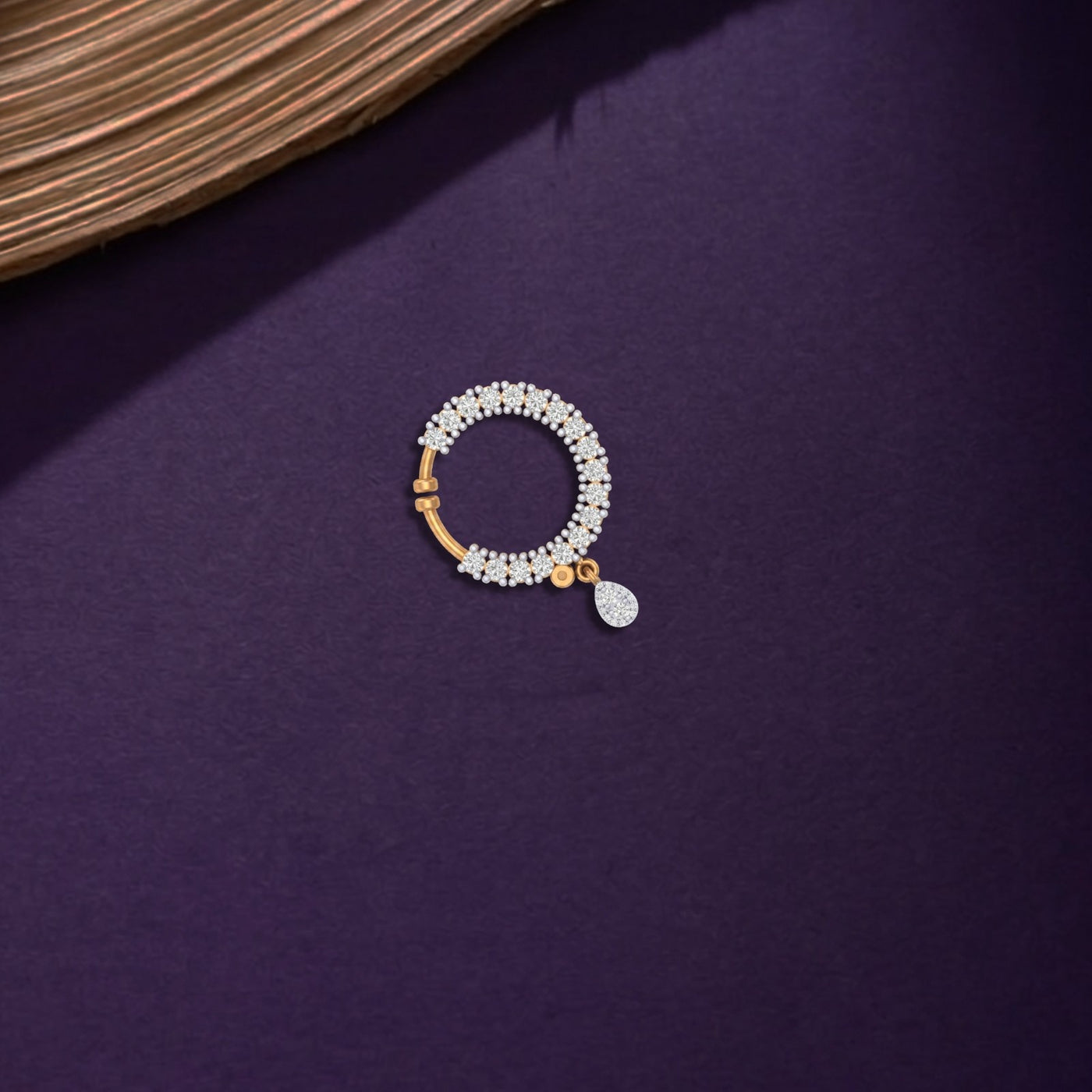 Yellow gold and diamond nose ring with decorative elements on a purple surface
