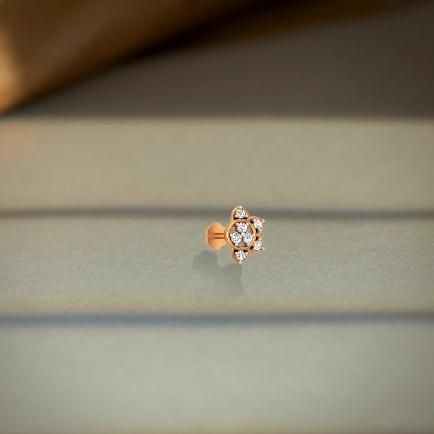yellow gold and diamond stud nose pin accents on a soft fabric background