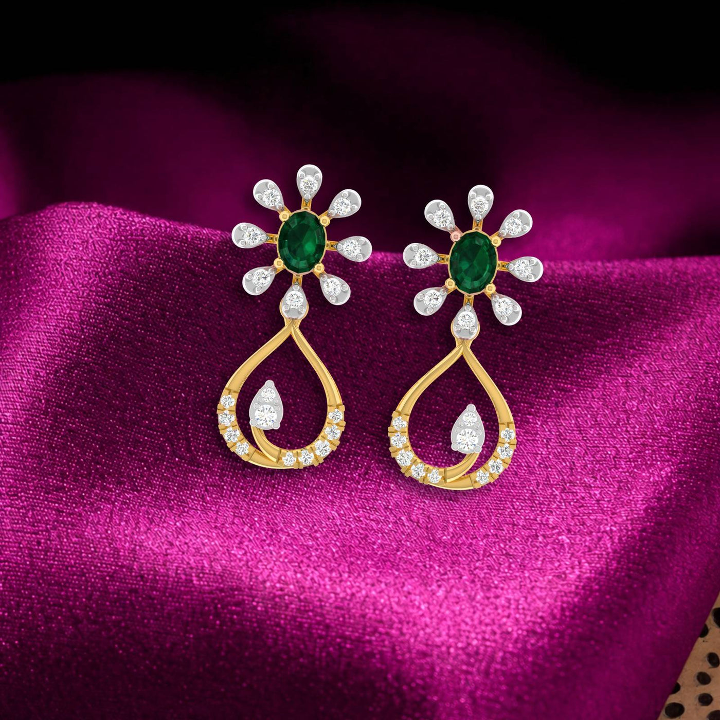 Gold and diamond drop earring with gemstone on a pink fabric background.