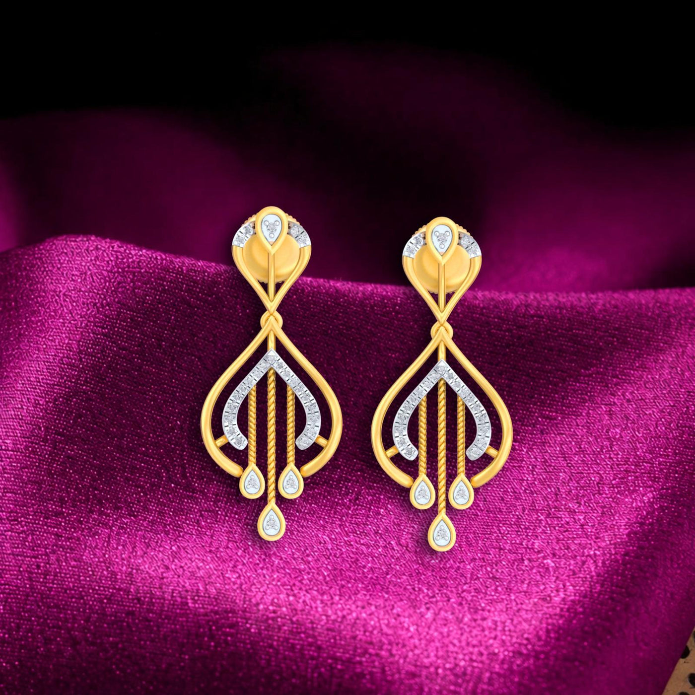 A pair of yellow gold and diamond drop earrings, displayed on a rich magenta  fabric background.