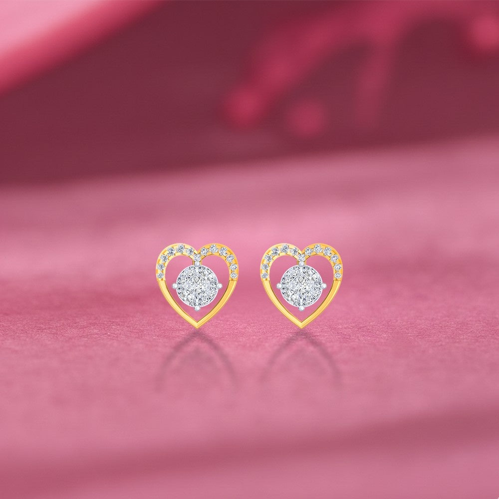 Heart-shaped earrings with gold frames and diamond on a pink surface. 