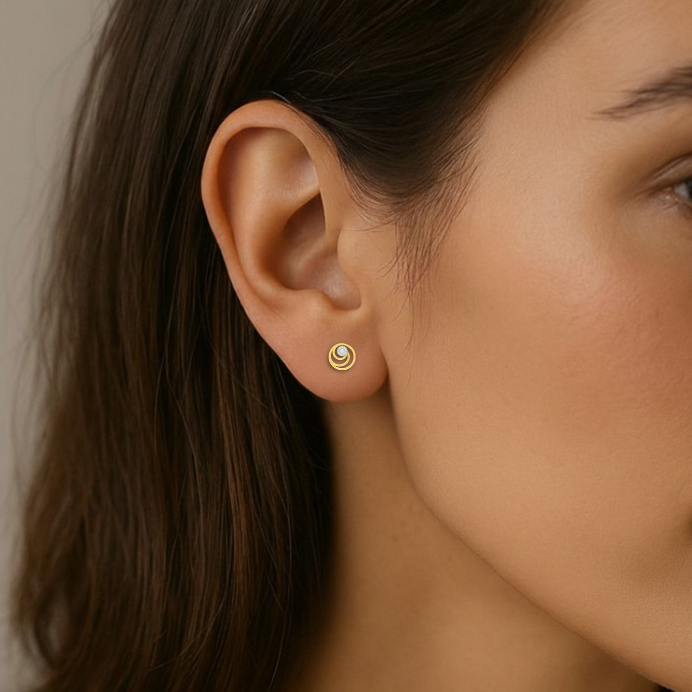 Close-up of a woman's ear wearing a gold and diamond stud earring.
