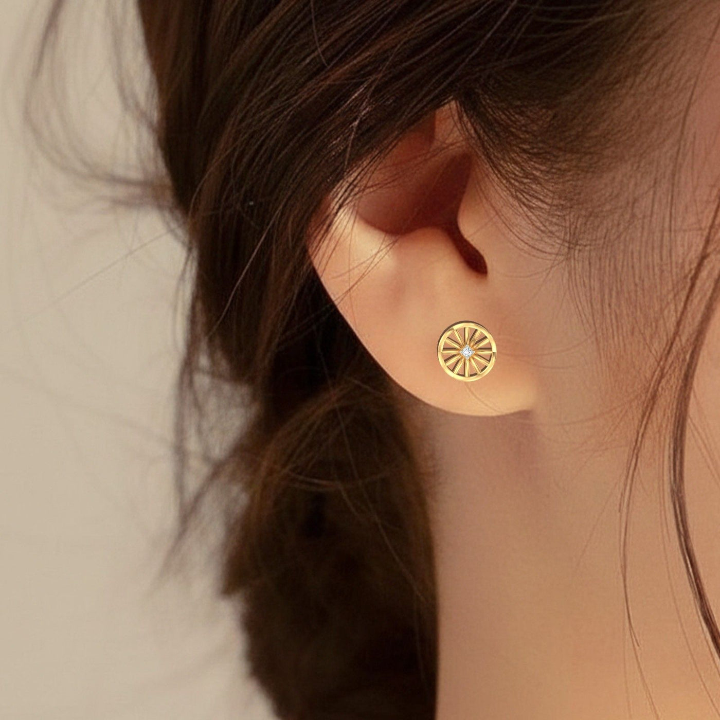 Close-up of a person wearing a gold and diamond stud earring 