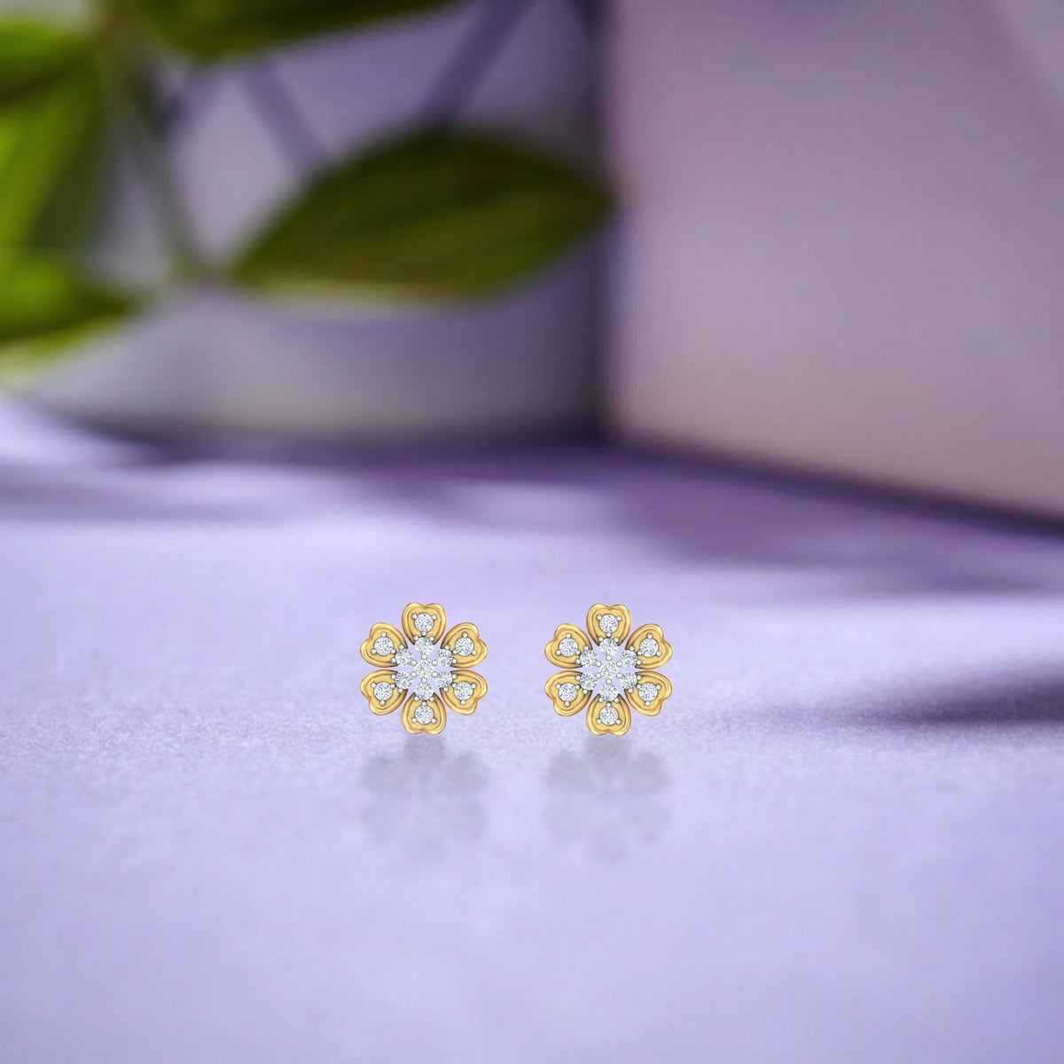 Gold flower-shaped earrings with a central diamonds on a purple fabric background.