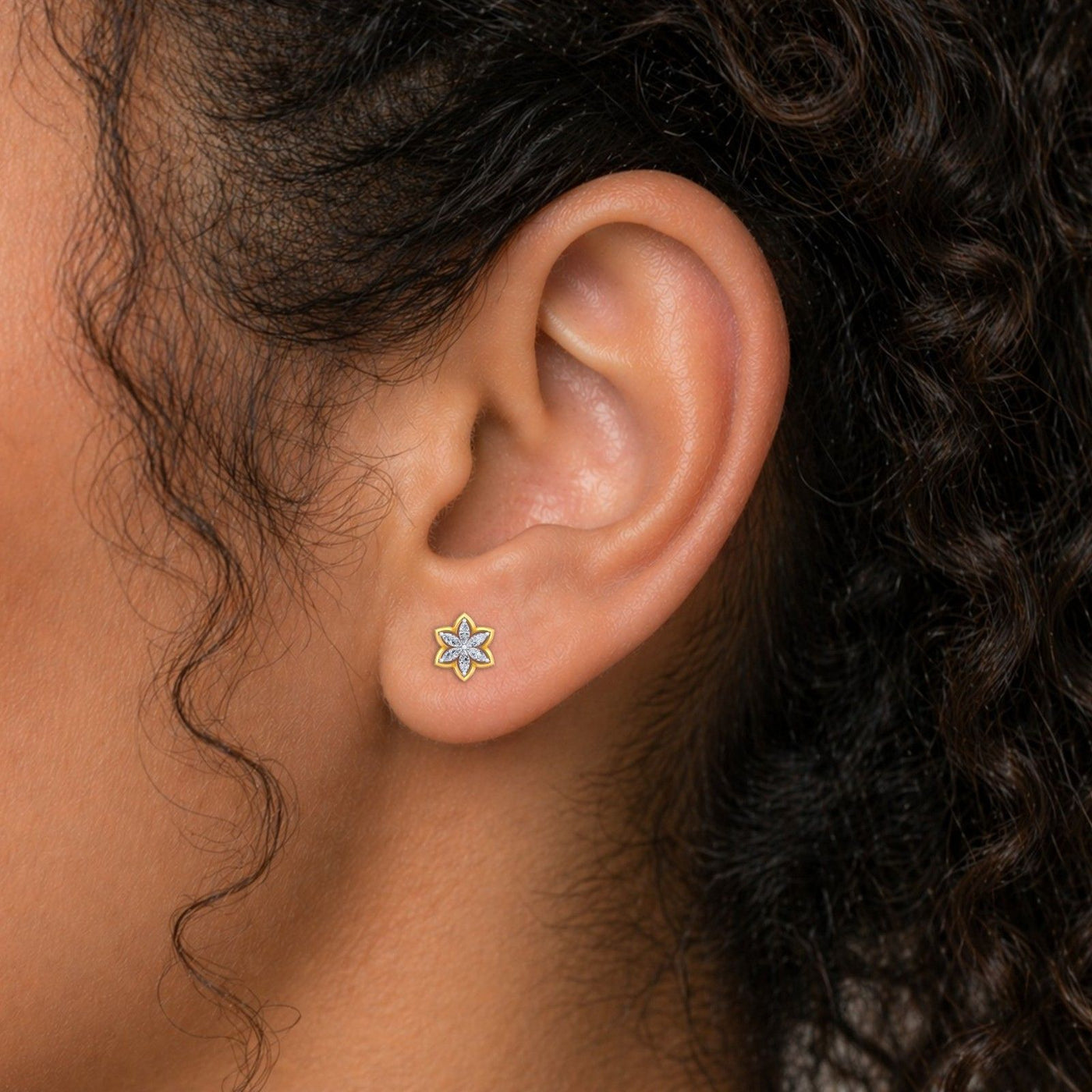 Close-up shot of gold and diamond floral-shaped stud earrings.