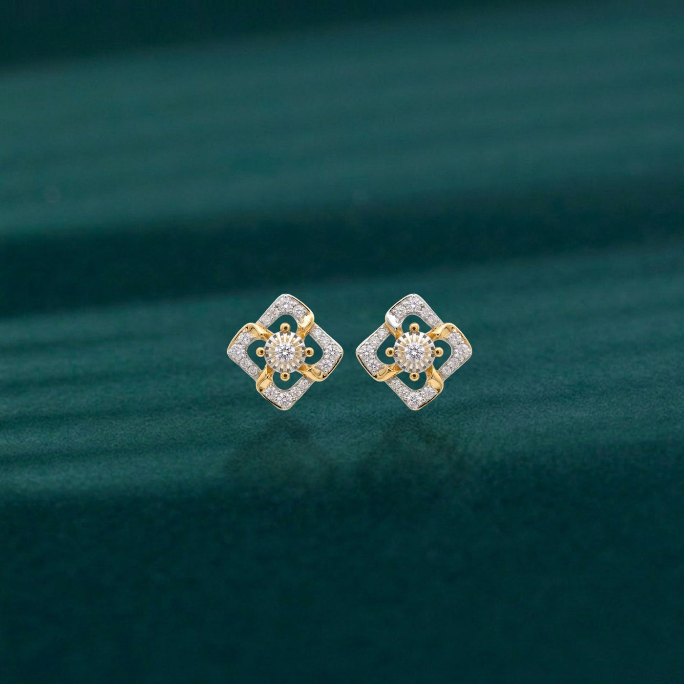 Pair of gold earrings with diamond-like stones on a teal background.