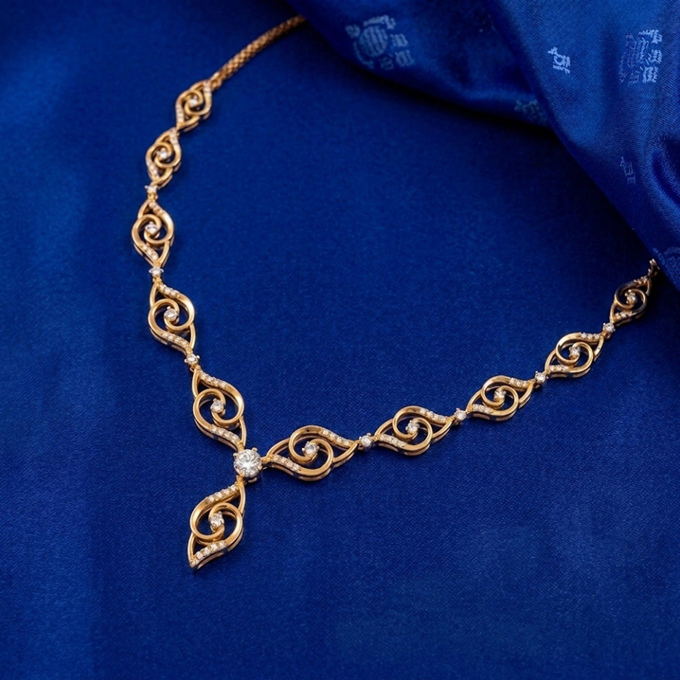 Gold necklace with intricate design on a blue fabric background