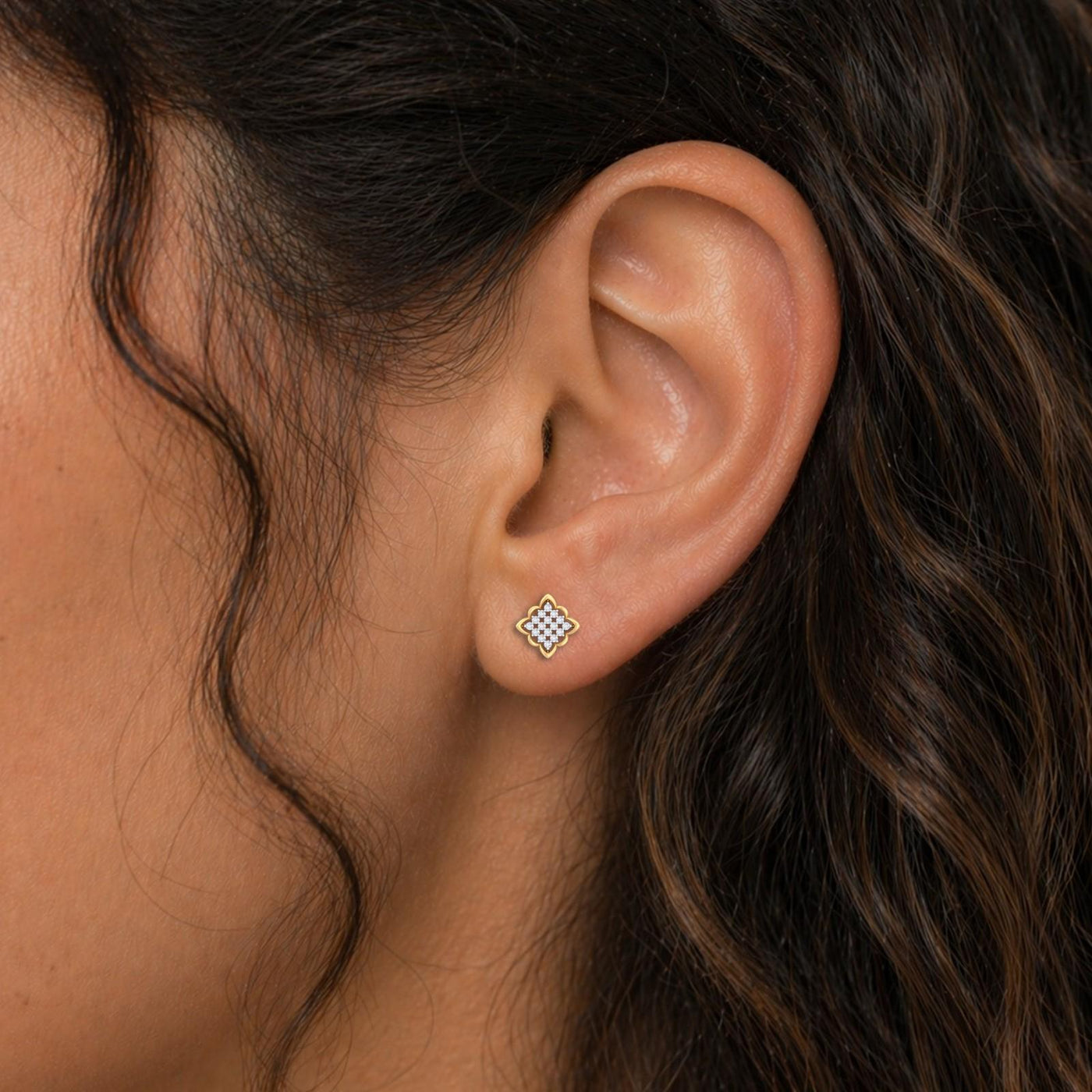 Close-up shot of a gold and diamond stud earring with floral-shaped.