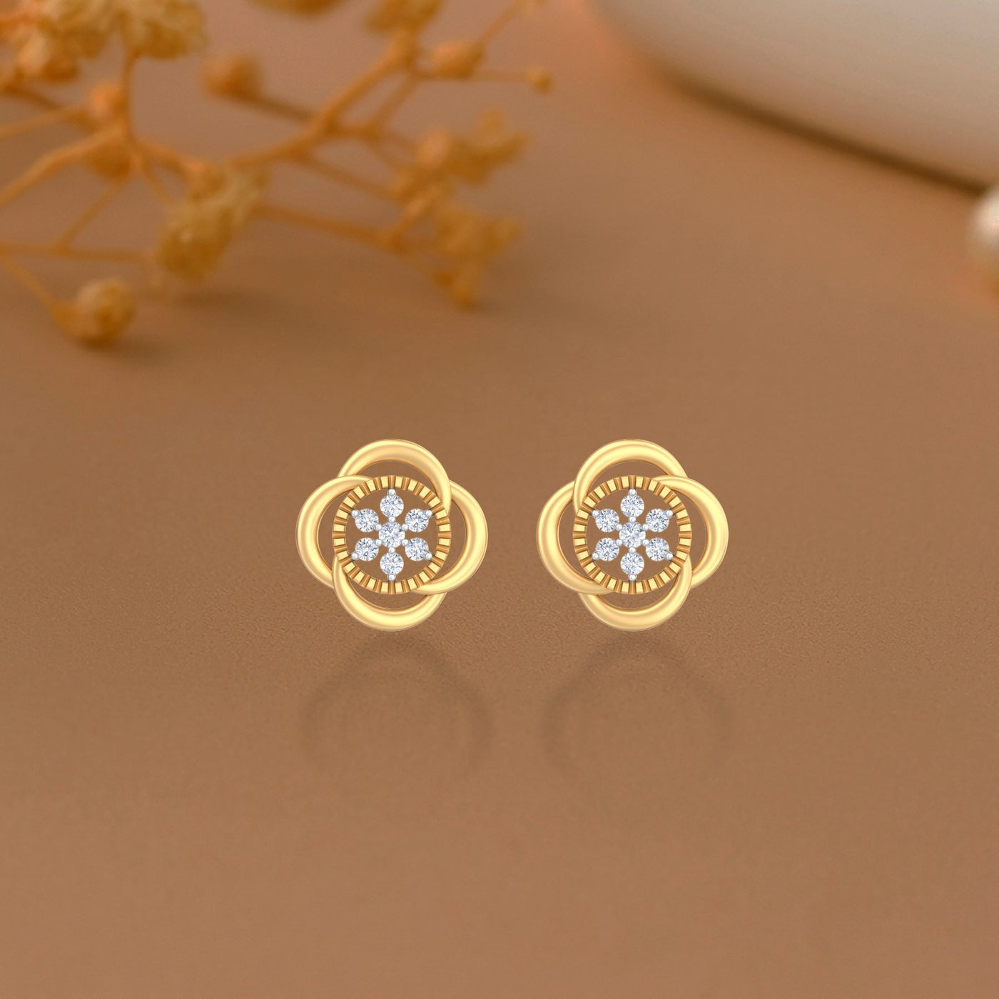Gold and diamond stud earring with floral-design on a brown background.