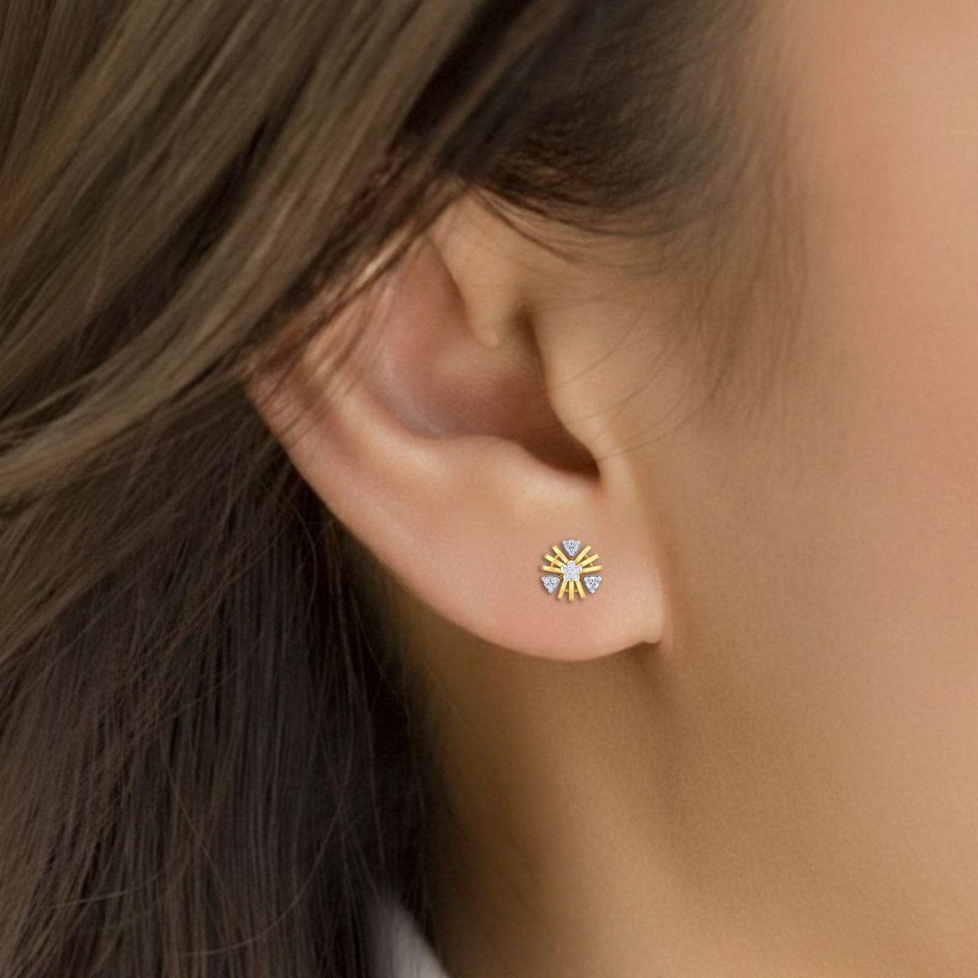 Close-up of an ear wearing a gold and diamond earring.