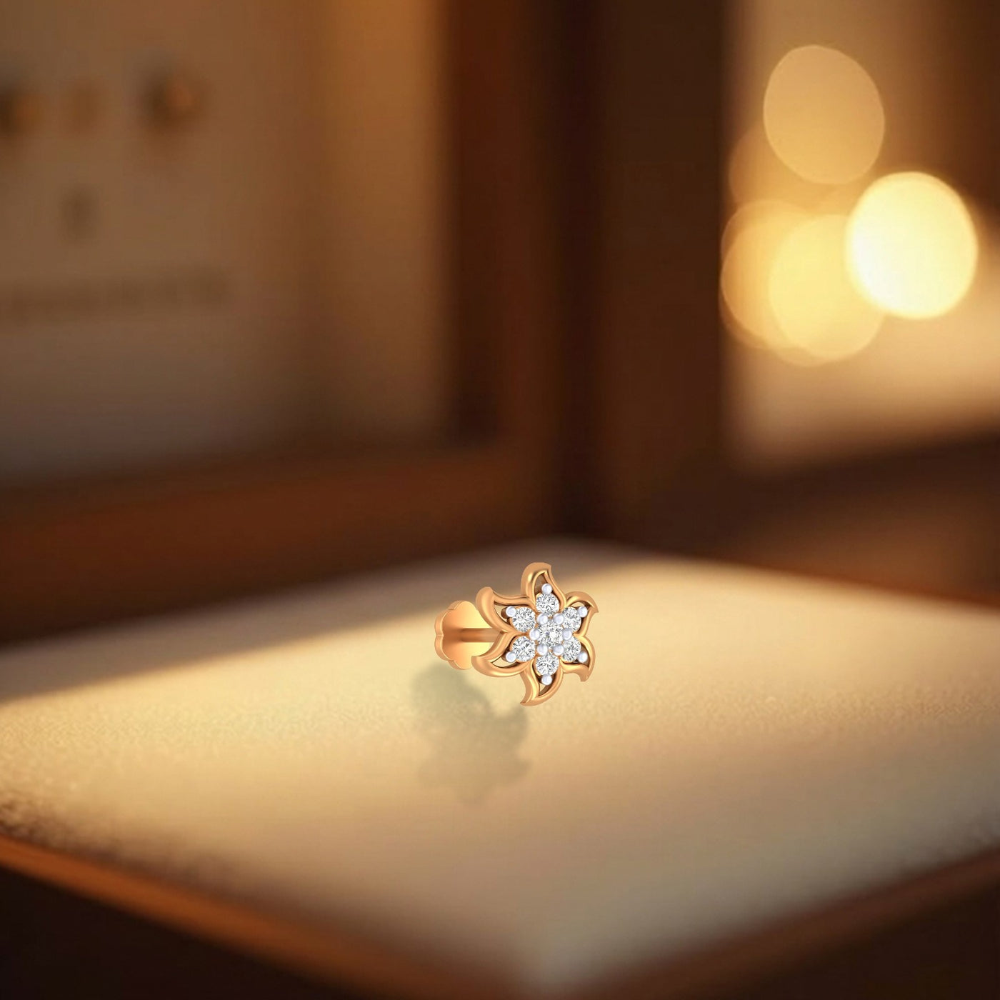 Yellow gold and diamond stud nose pin on a soft focus background