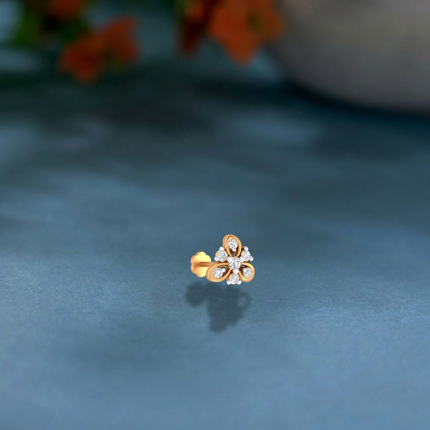 Yellow Gold and diamond stud nose pin floral design on a dark textured surface