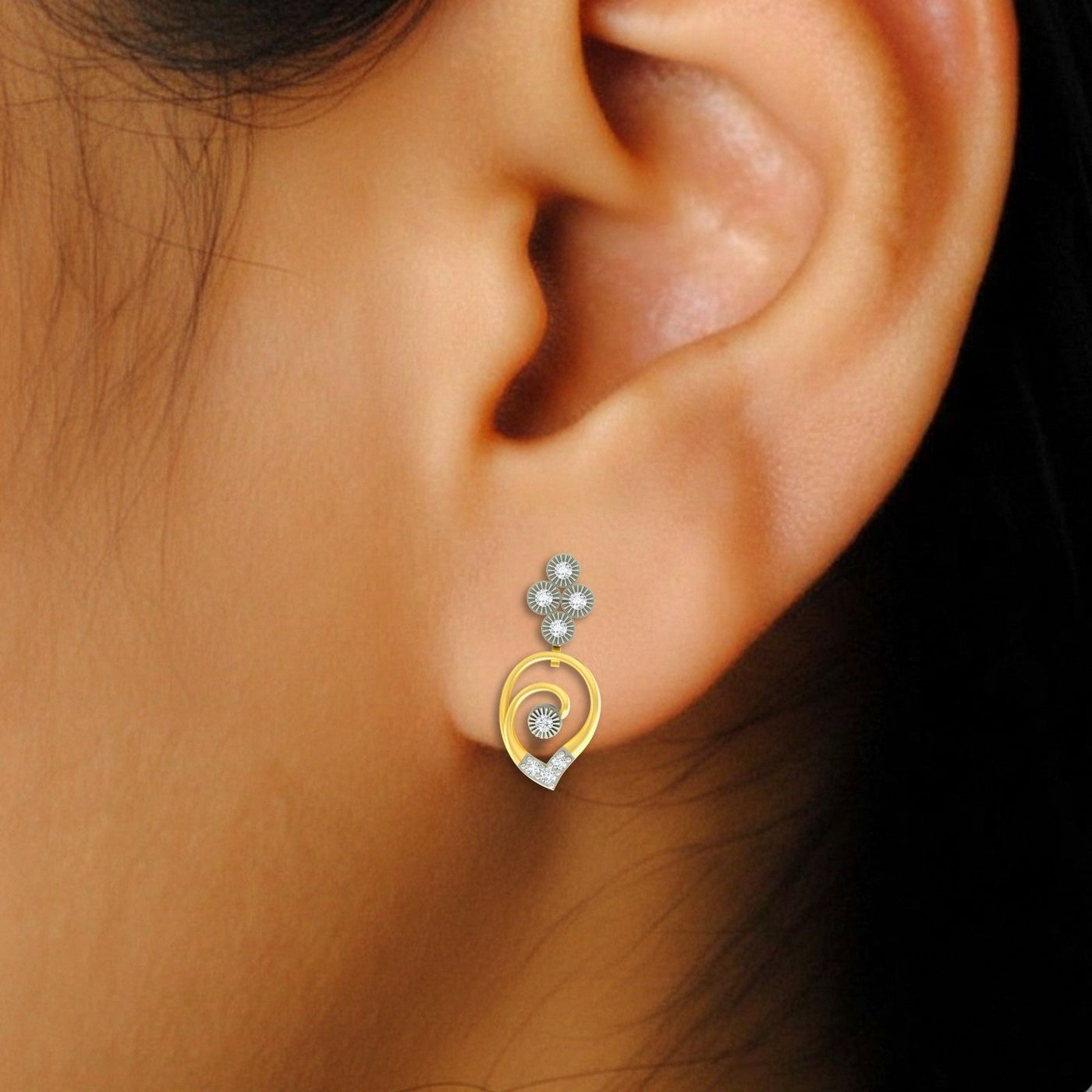 Close-up of an ear wearing a gold and diamond drop earring.