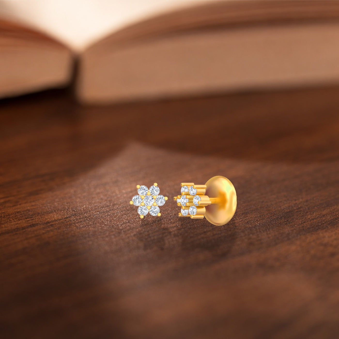 Gold and diamond floral stud earrings on a wooden surface 