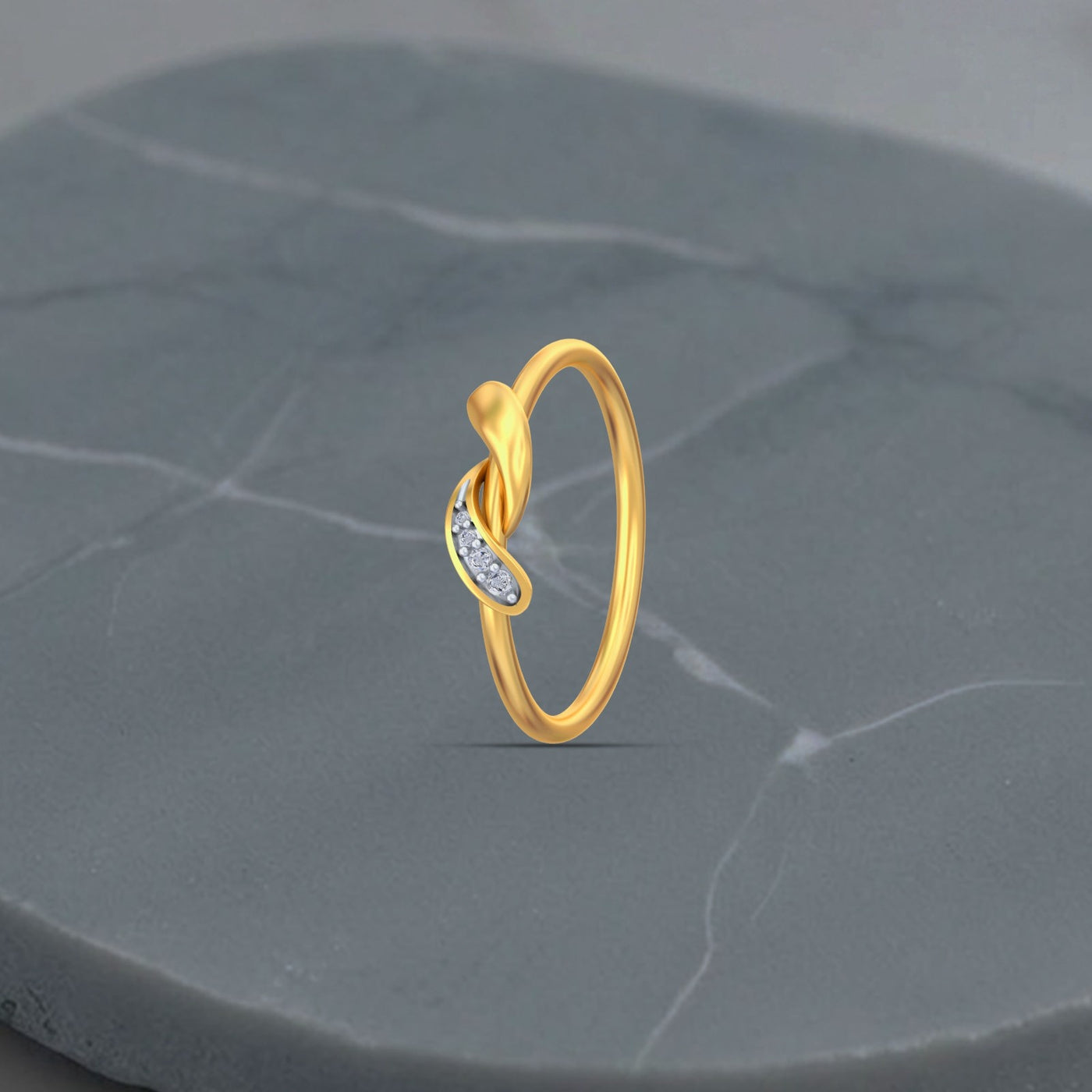 Gold ring with small diamonds on a gray stone surface

