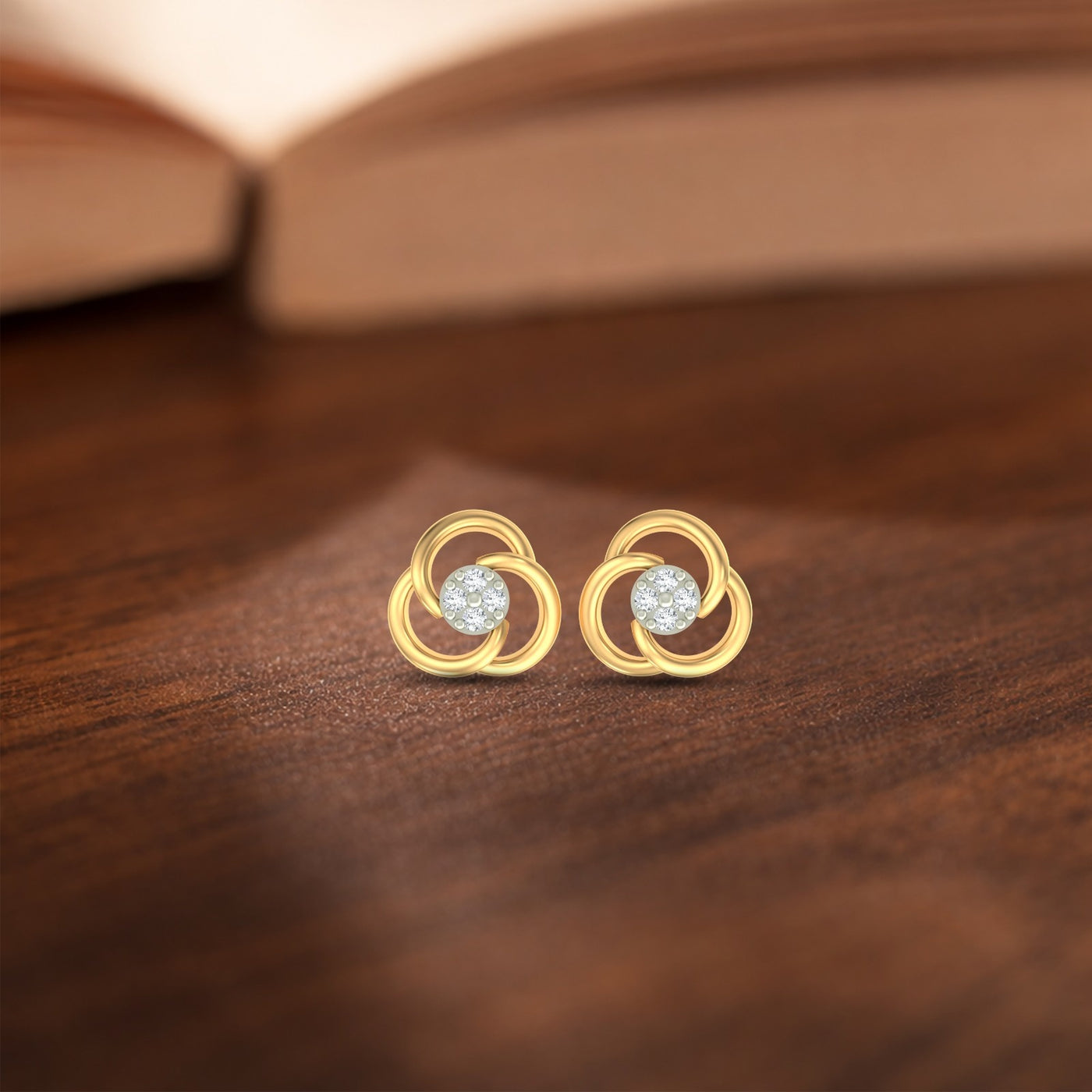 Gold and diamond stud earrings with circular design on a wooden surface