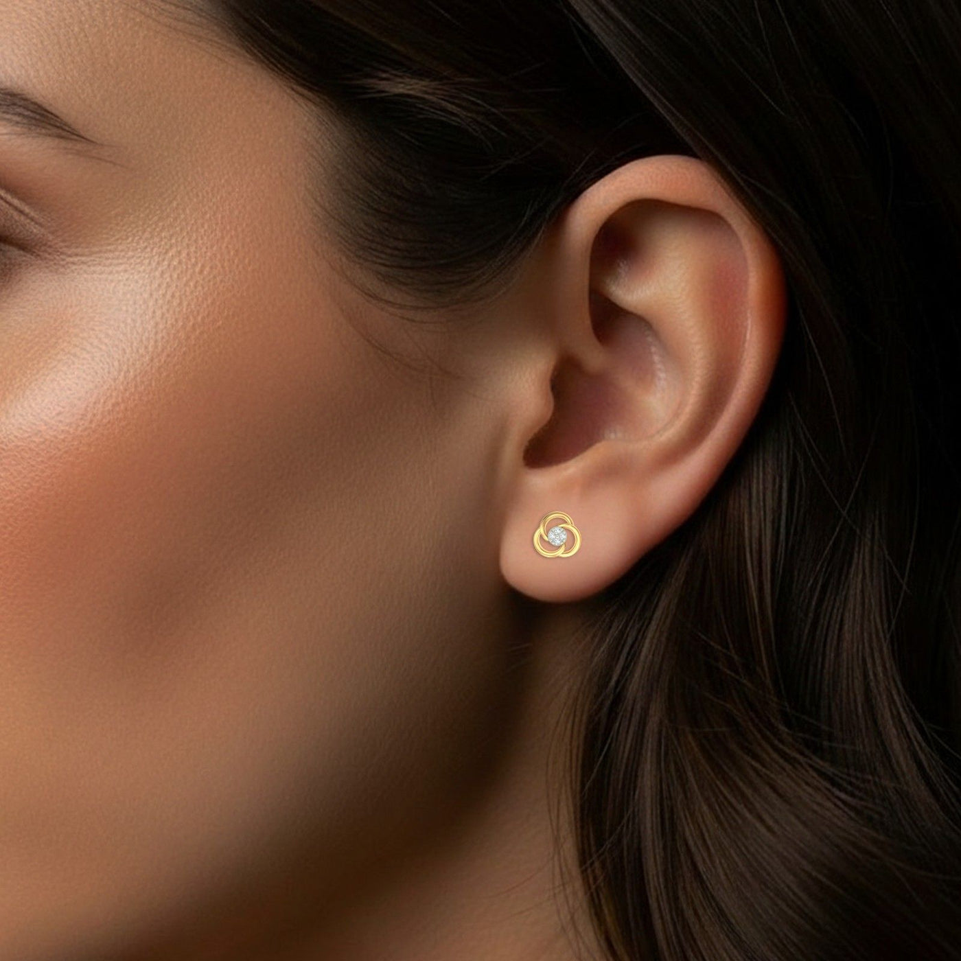 Close-up of an ear wearing a gold and diamond stud earring.