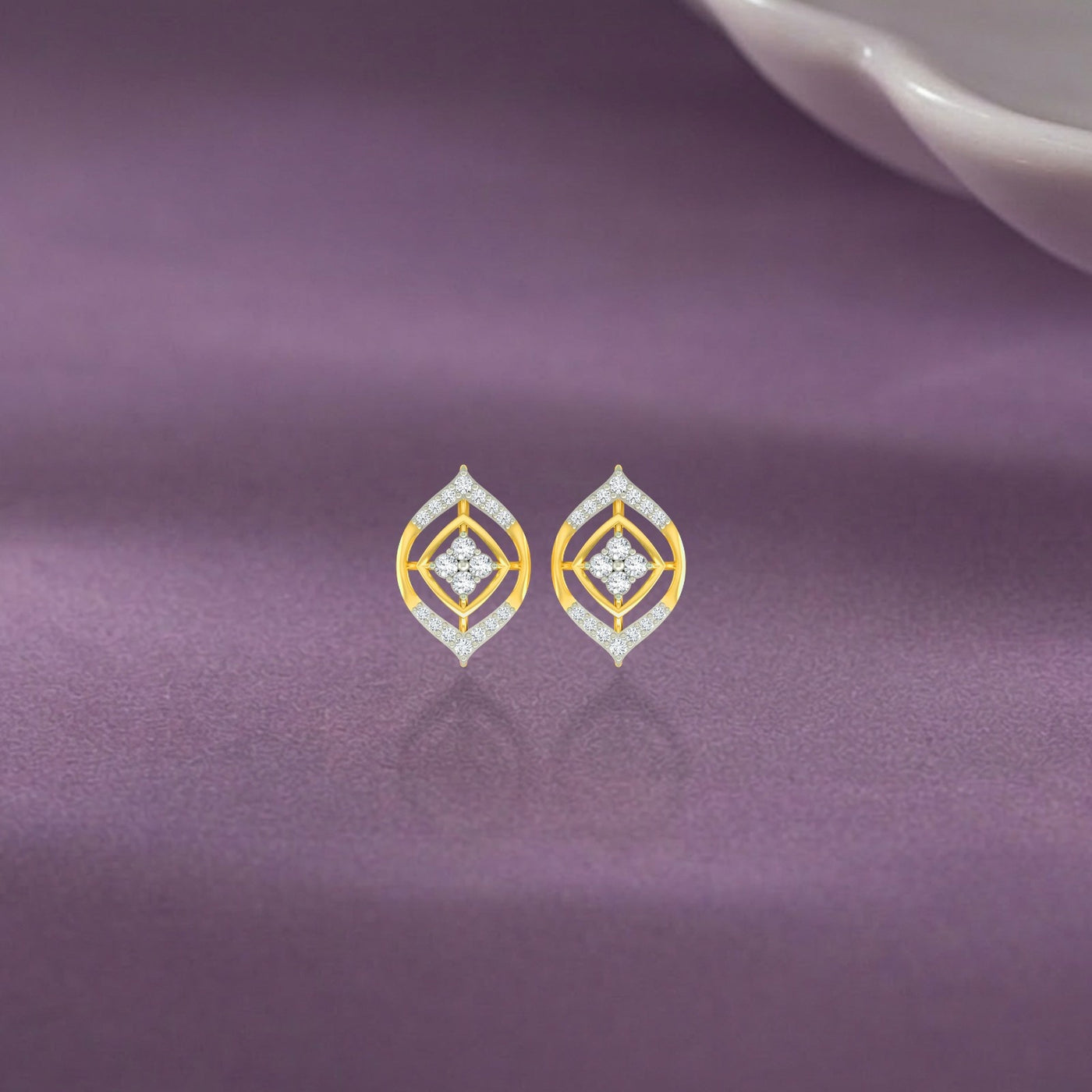 Pair of gold and diamond stud earrings on a purple background.
