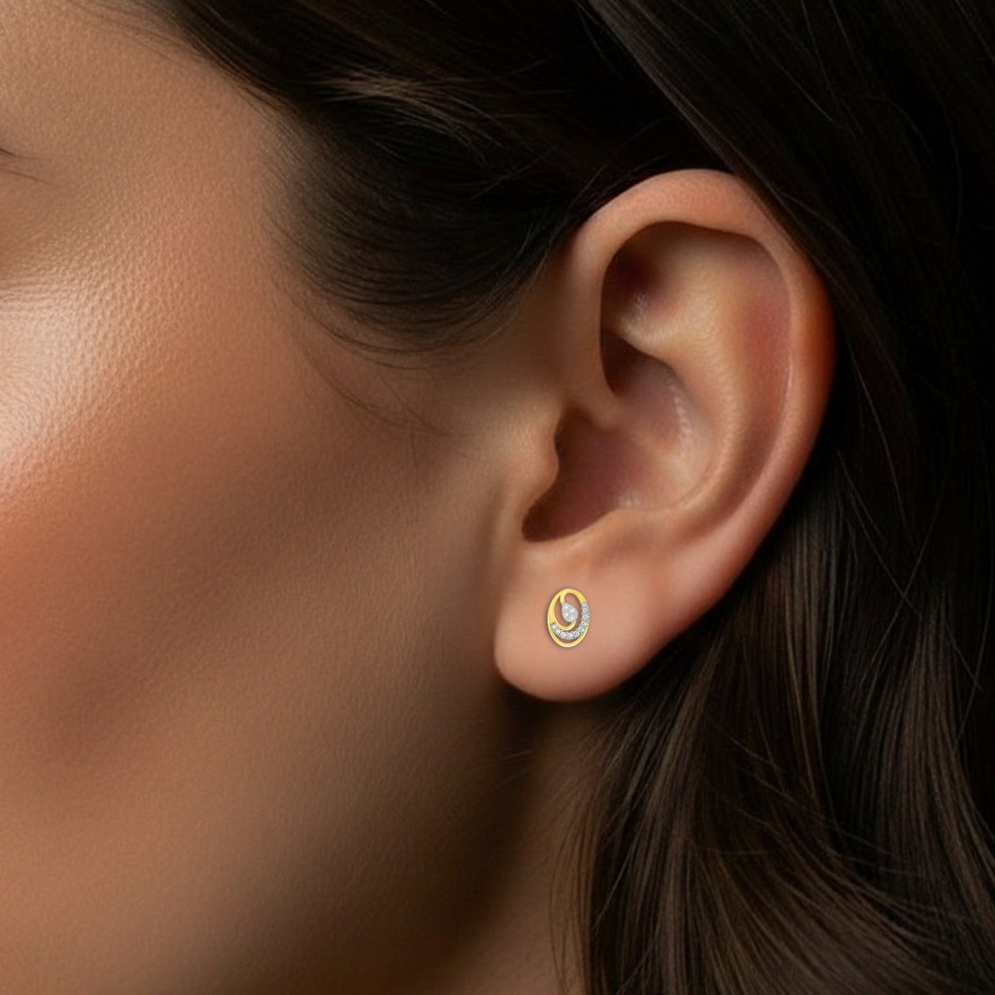 Close-up of an ear wearing a gold and diamond stud earring.