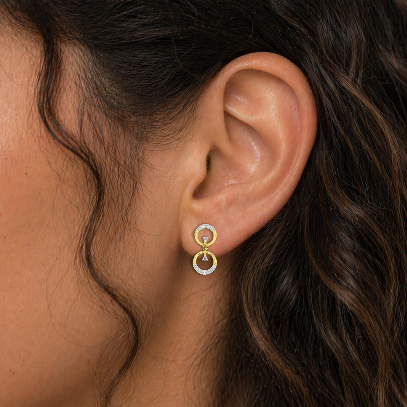 Close-up shot of a gold and diamond earrings with circular designs.