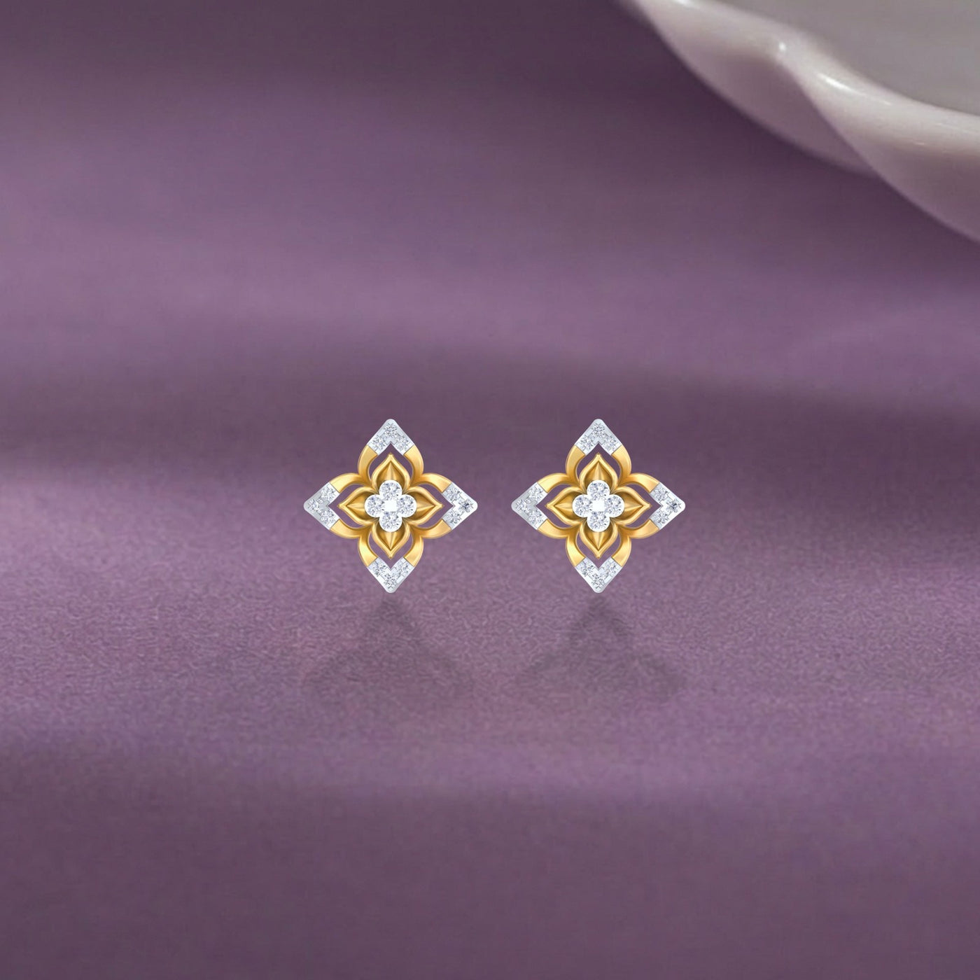 Gold and diamond stud earring with floral-design on a purple surface.