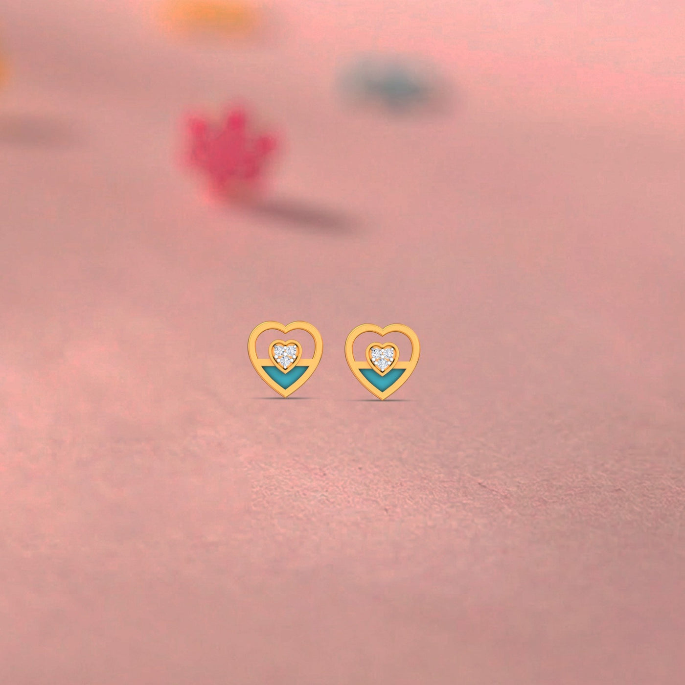 Gold and diamond heart-shaped stud earrings on a pink background