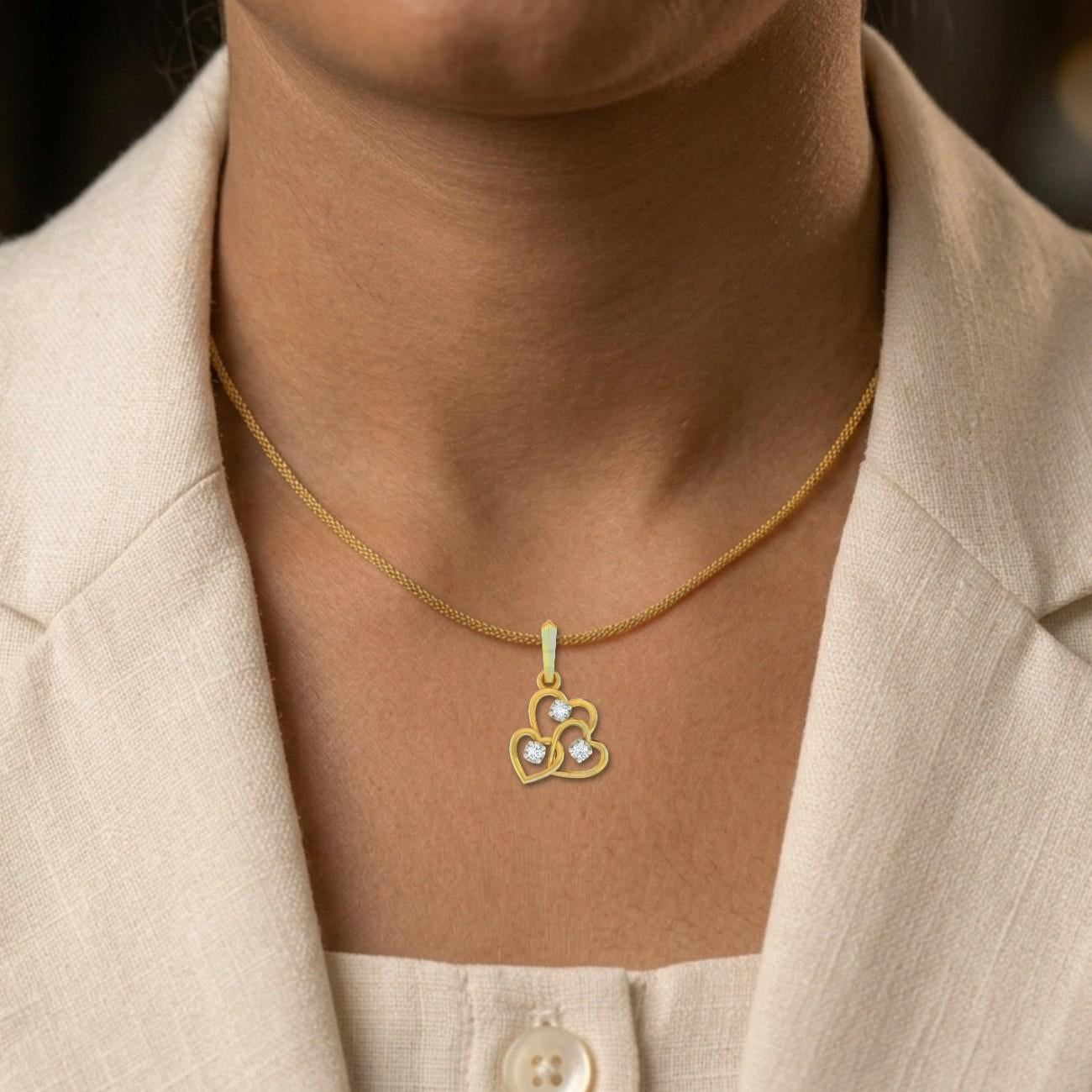 Gold necklace with a pendant worn by a person in a beige outfit.