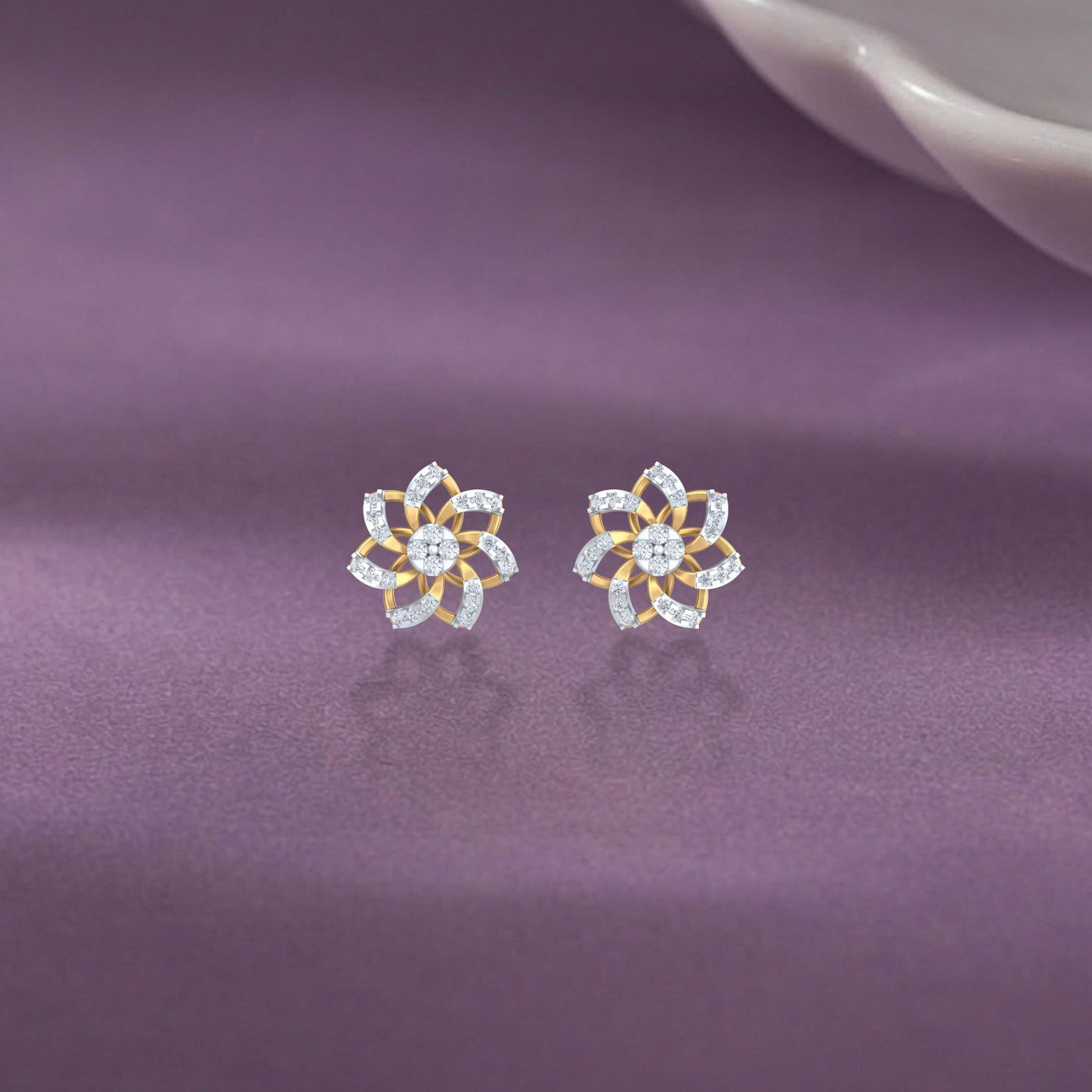 Gold and diamond stud earring with floral-design on a purple fabric background.