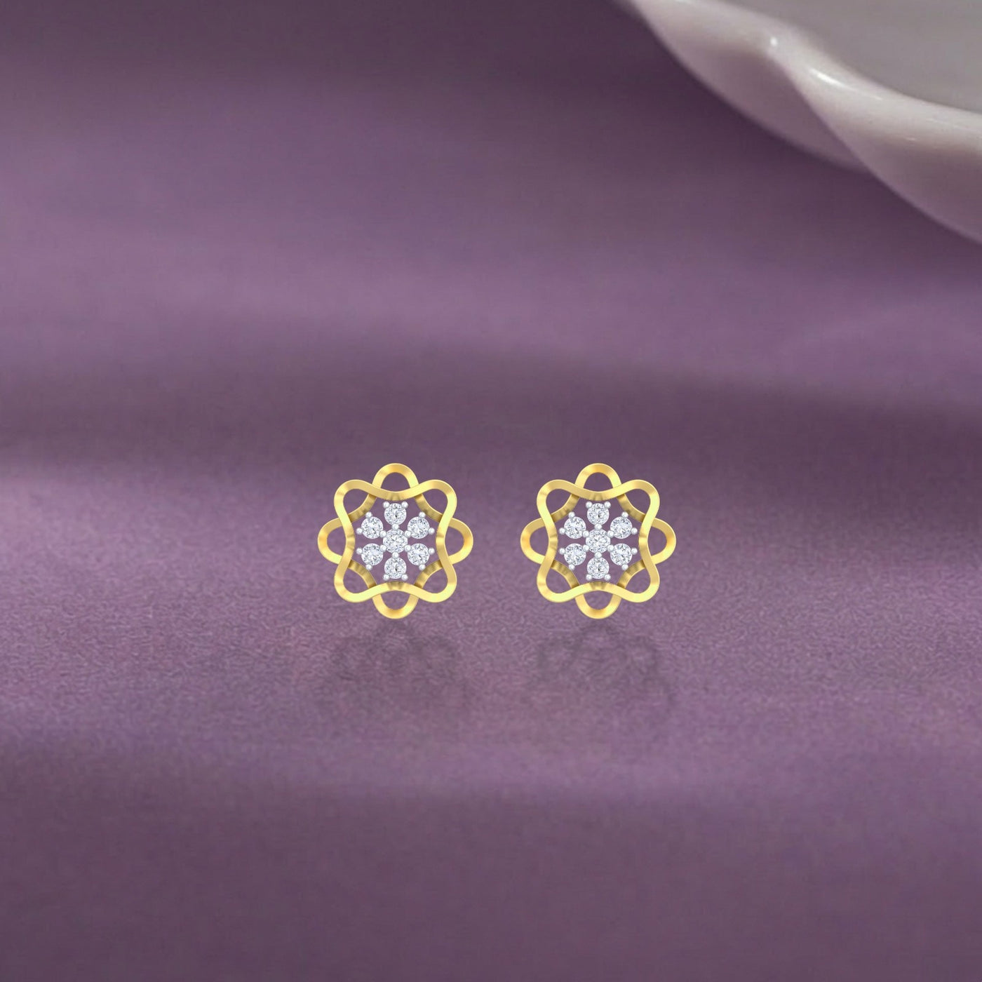 Gold and diamond stud earring with floral-design on a purple fabric background.