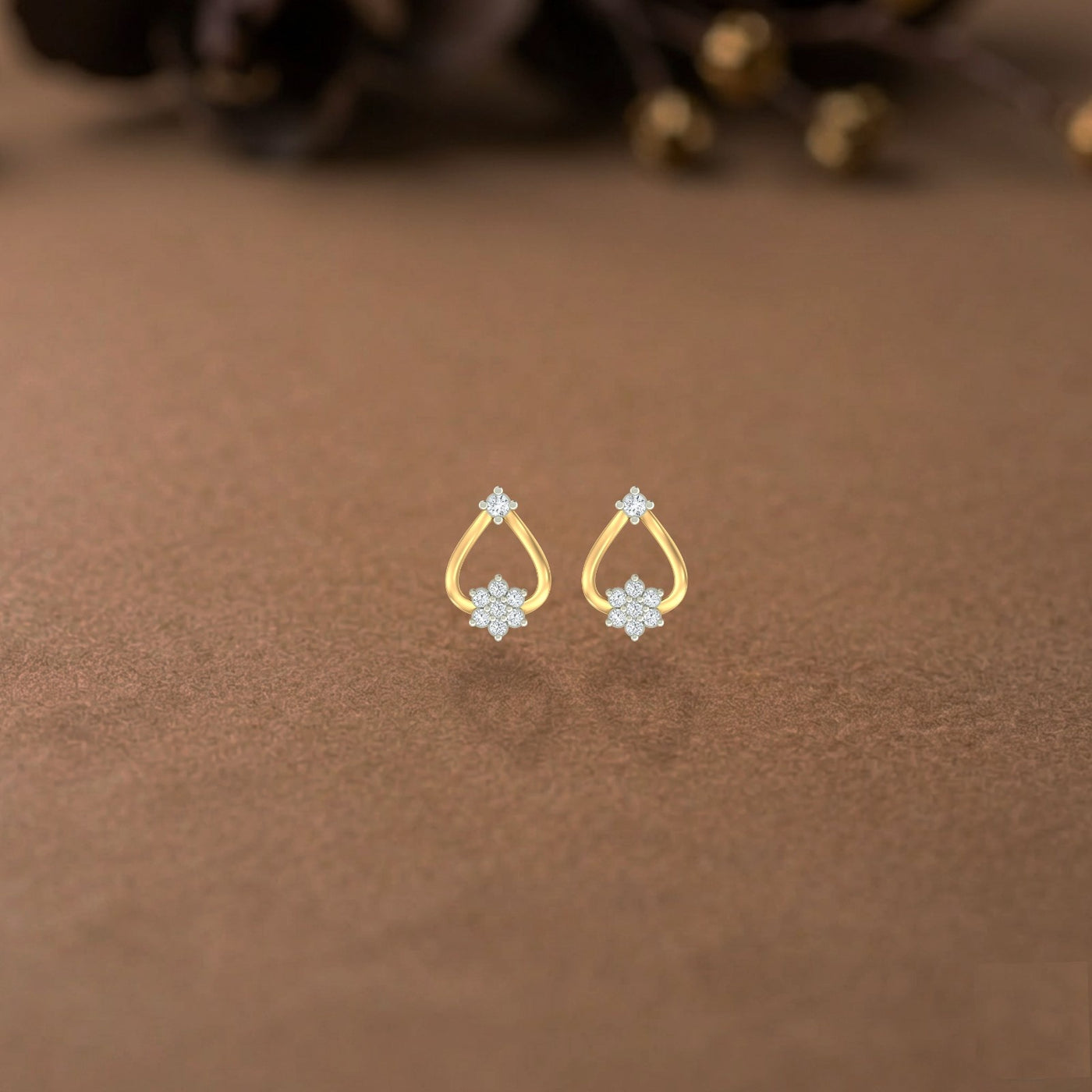 Gold and diamond stud earrings with floral design on a brown surface