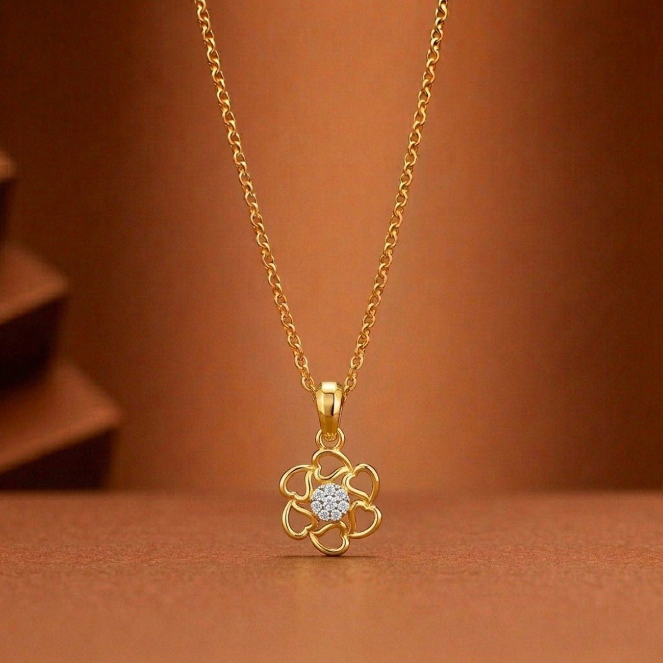 Gold necklace with a floral pendant on an orange background