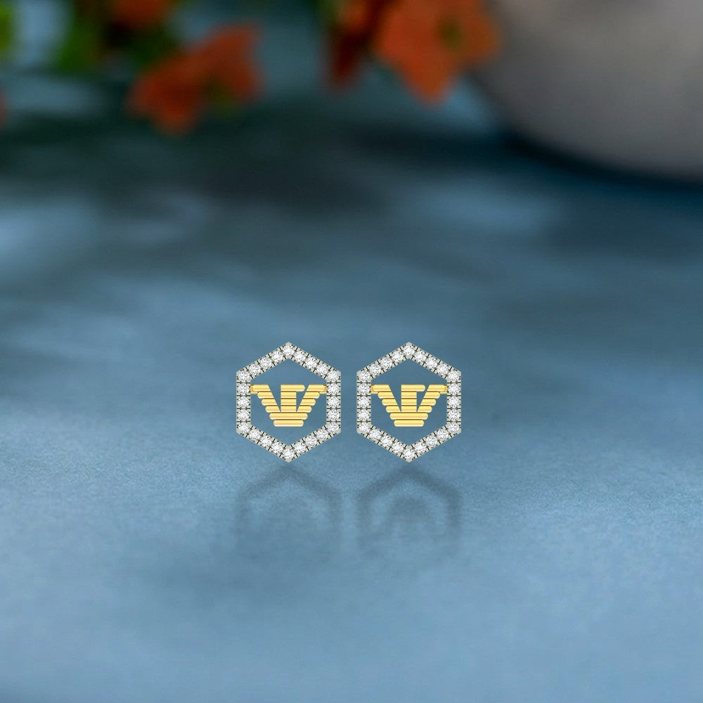 Gold and diamond-studded hexagonal frames earrings on a blue surface.