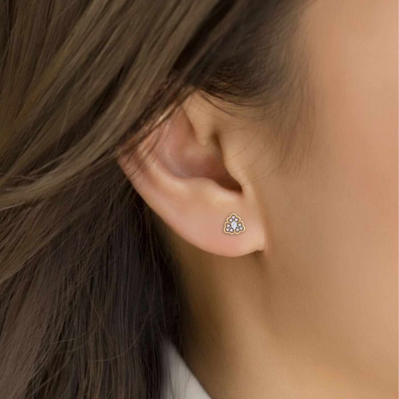 Close-up shot of a gold and diamond floral stud earrings.