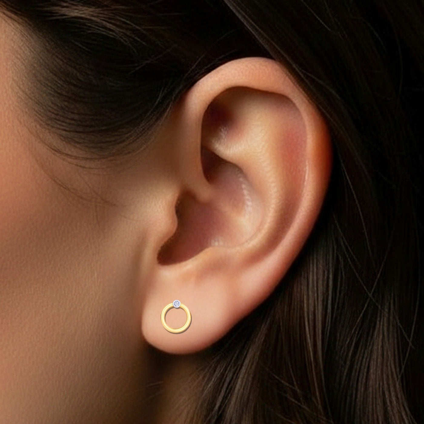 Close-up of an ear wearing a gold and diamond round-shaped stud earring 