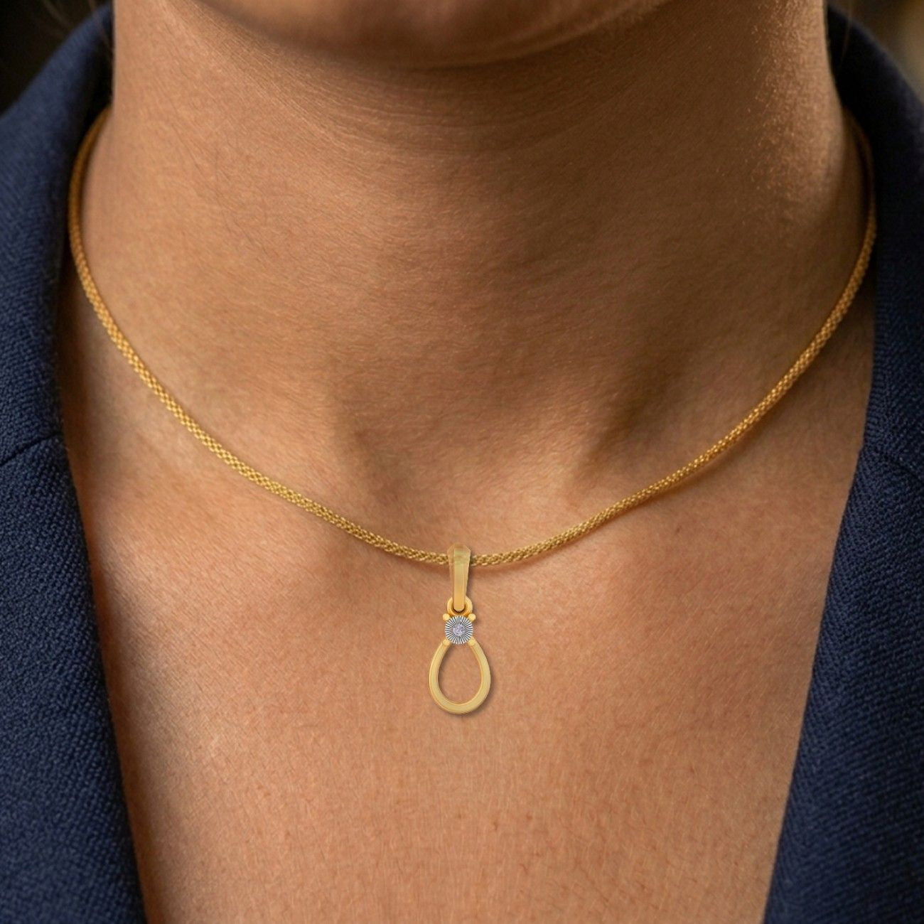 Gold necklace with a blue gemstone pendant on a person's neck