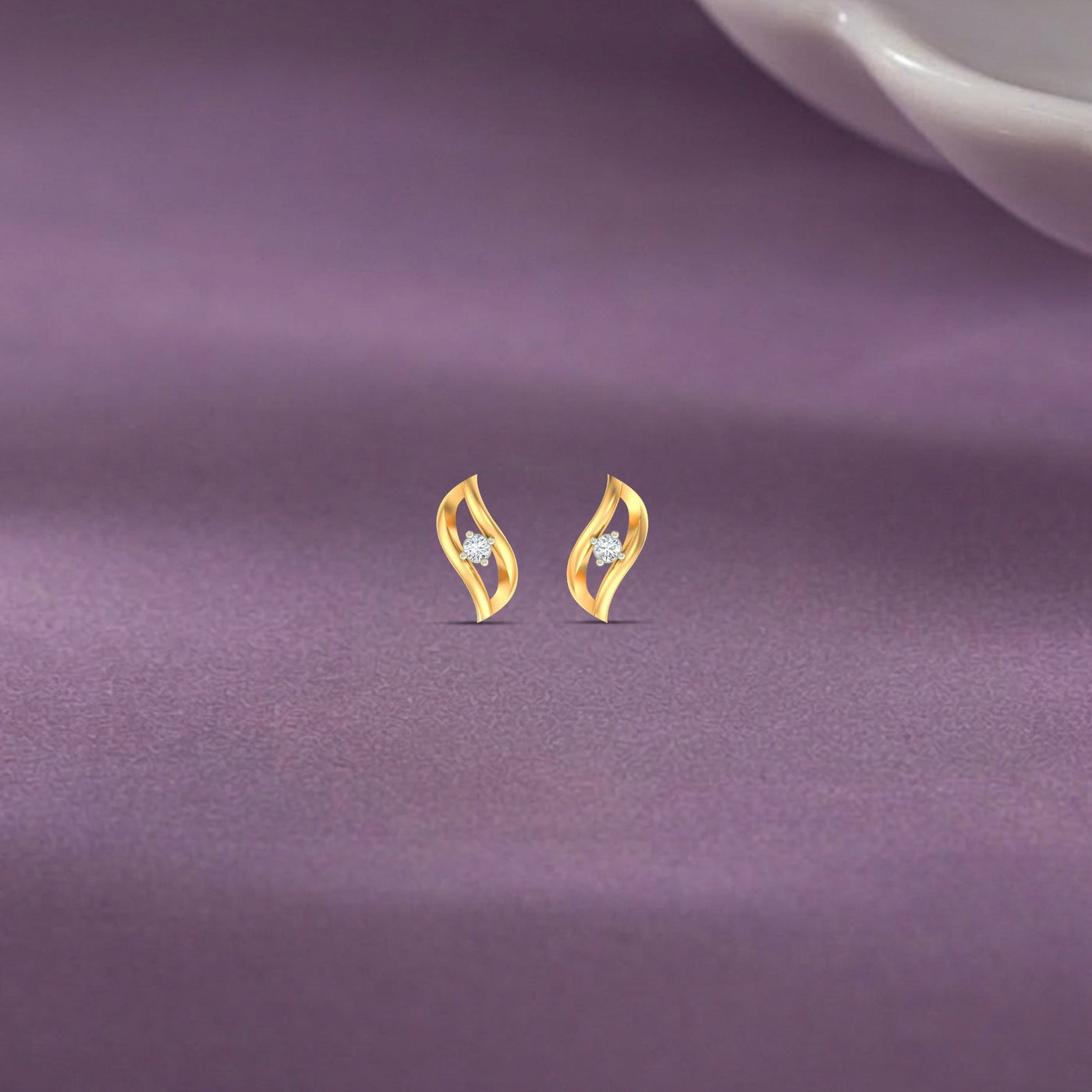 Gold & diamond women stud earring on a purple fabric background