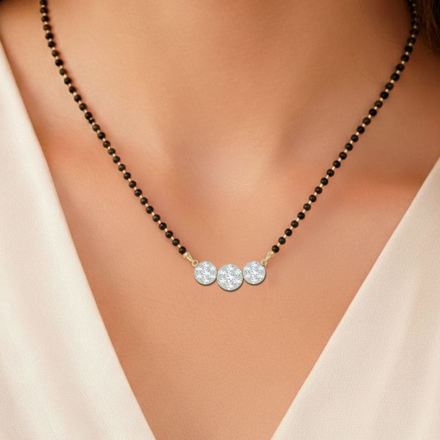 Mangalsutra with black beads and diamond pendants on a model wearing a beige top.