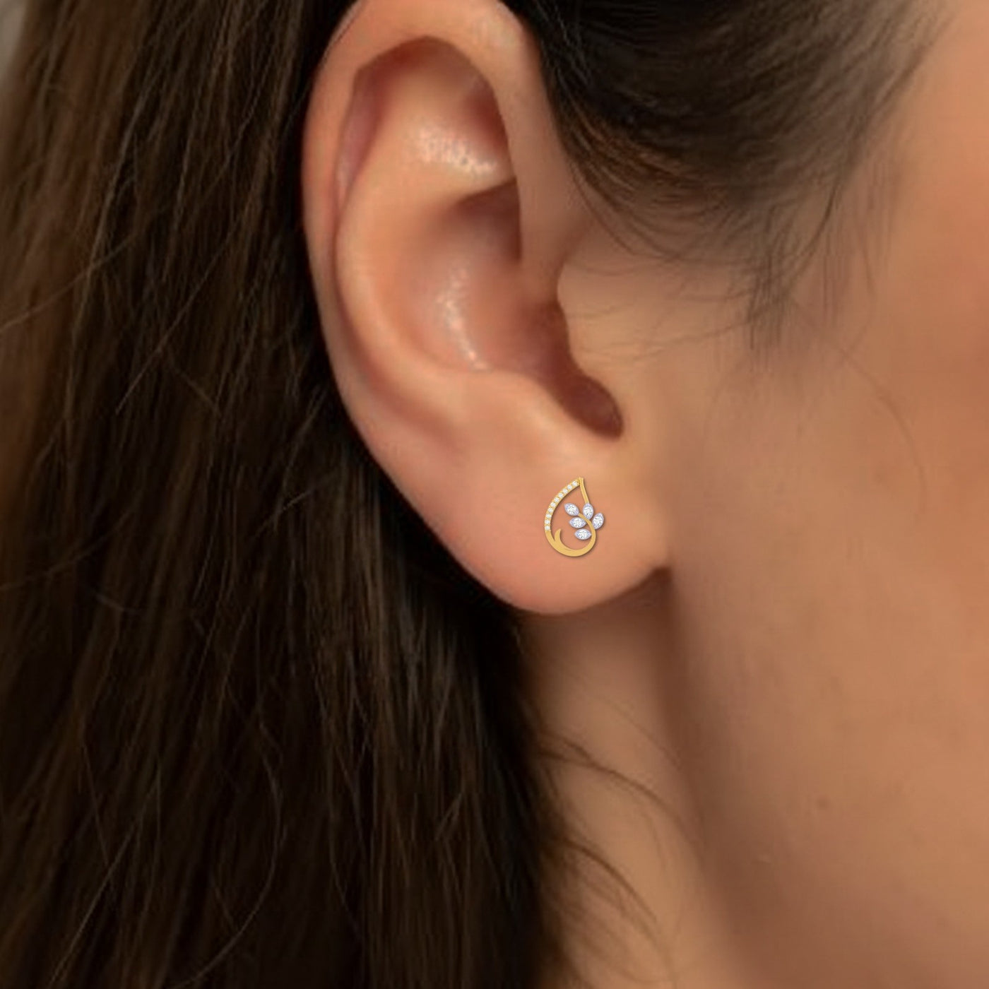 Gold and diamond stud earring with floral design worn by a person