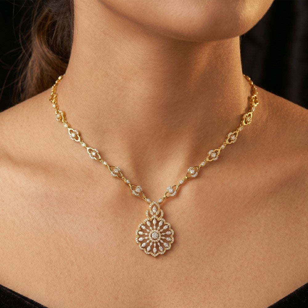 Gold necklace with a floral design on a person against a black background.