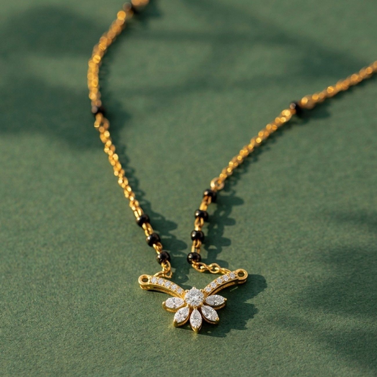 gold and diamond mangalsutra on green background 