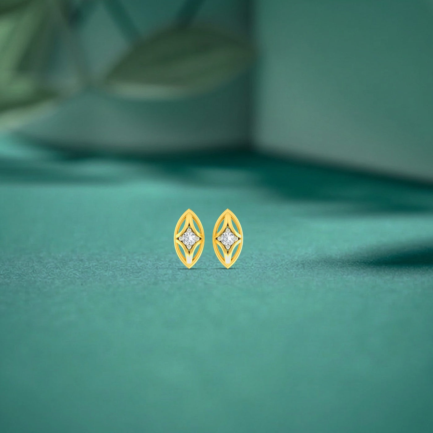 Gold and diamond stud earrings on a teal fabric background