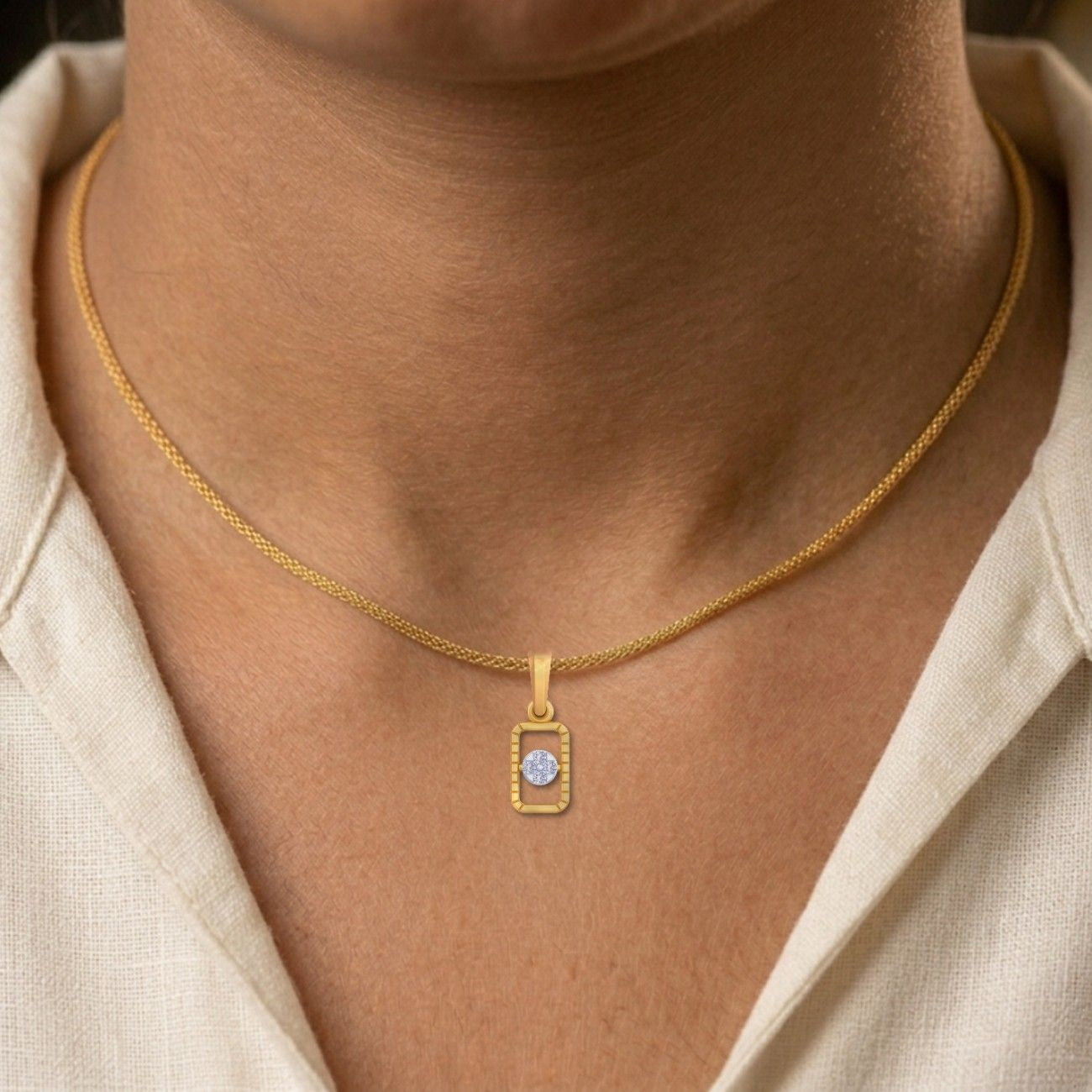 Gold necklace with a rectangular pendant worn by a person
