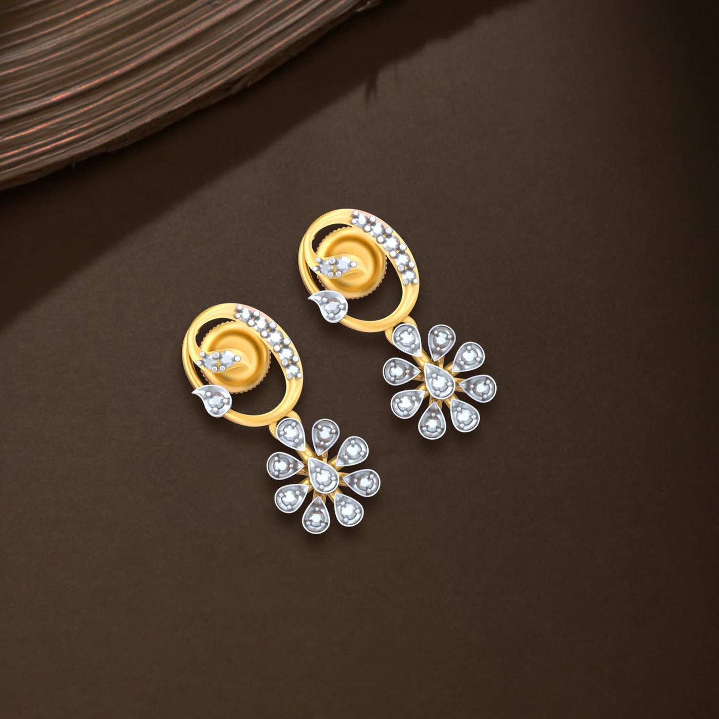 Gold and diamond drop earrings on a brown surface.