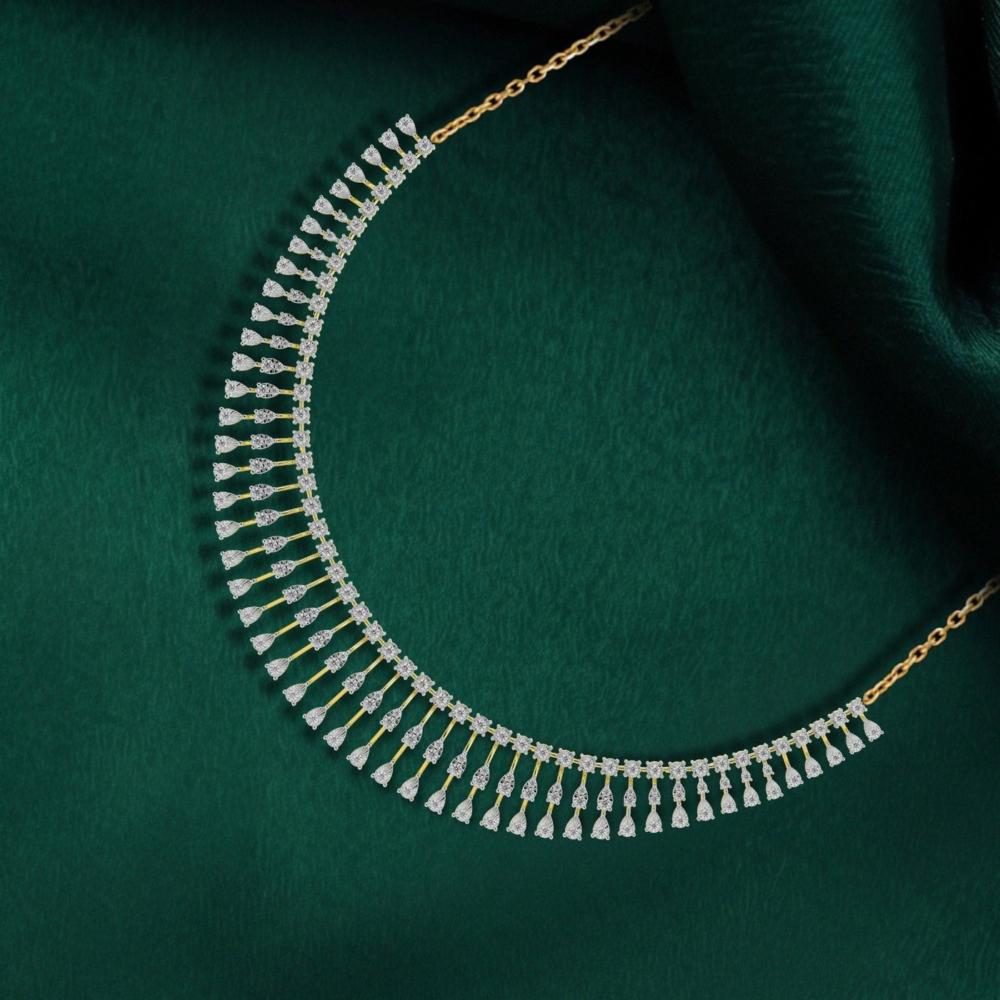 A gold and diamond necklace with a curved, tiered design, displayed on a draped dark green fabric background.