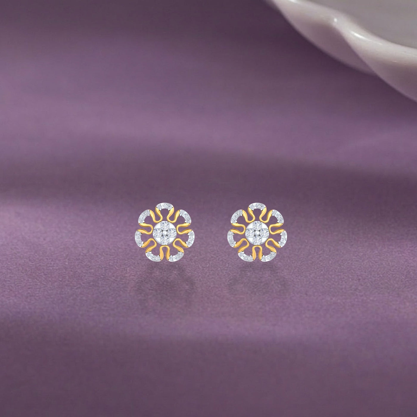 Gold and diamond stud earring with floral-design on a purple surface. 